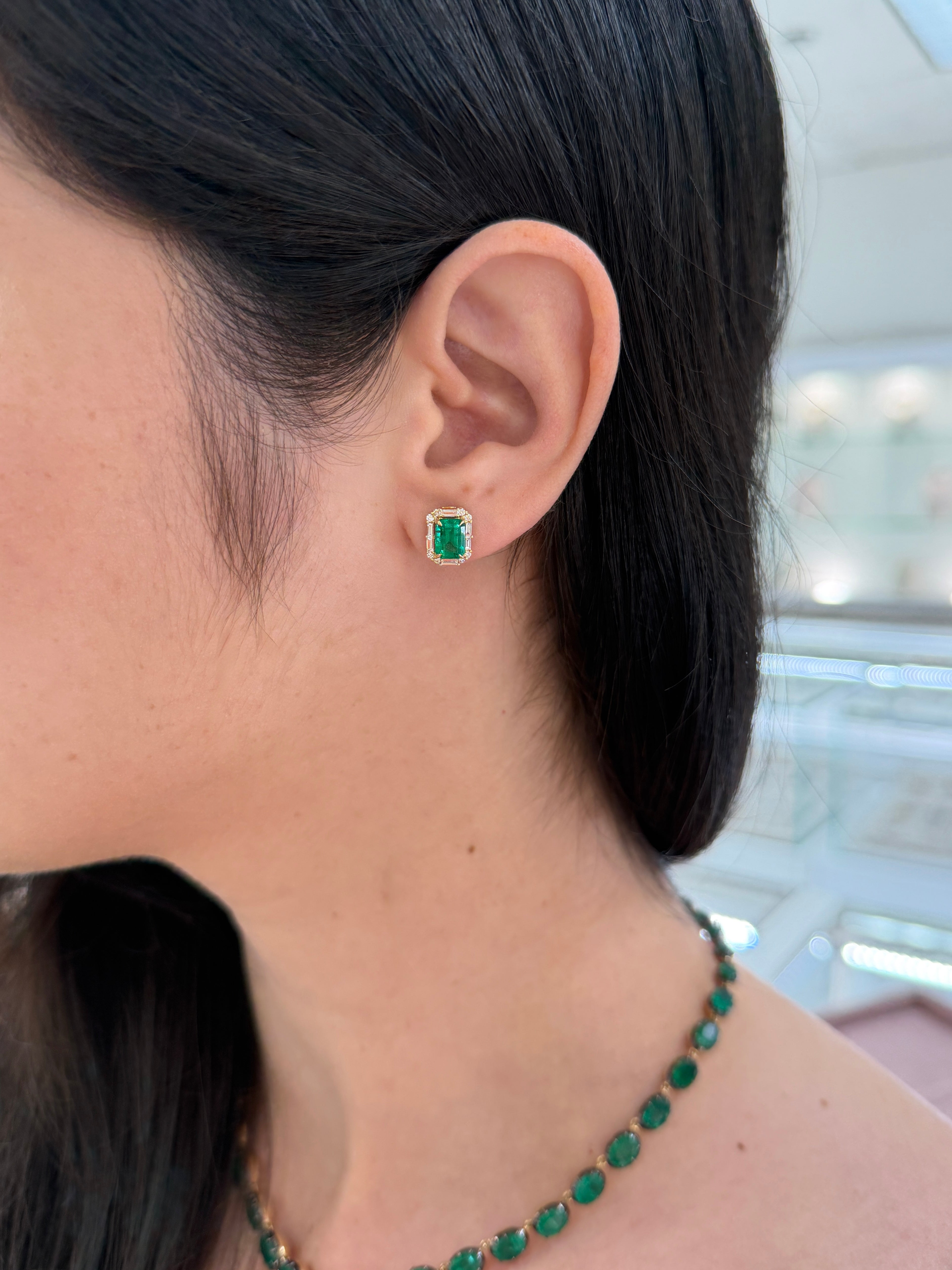 18K gold emerald and diamond halo stud earrings featuring rich green emeralds and baguette diamonds, crafted by JR Colombian Emeralds