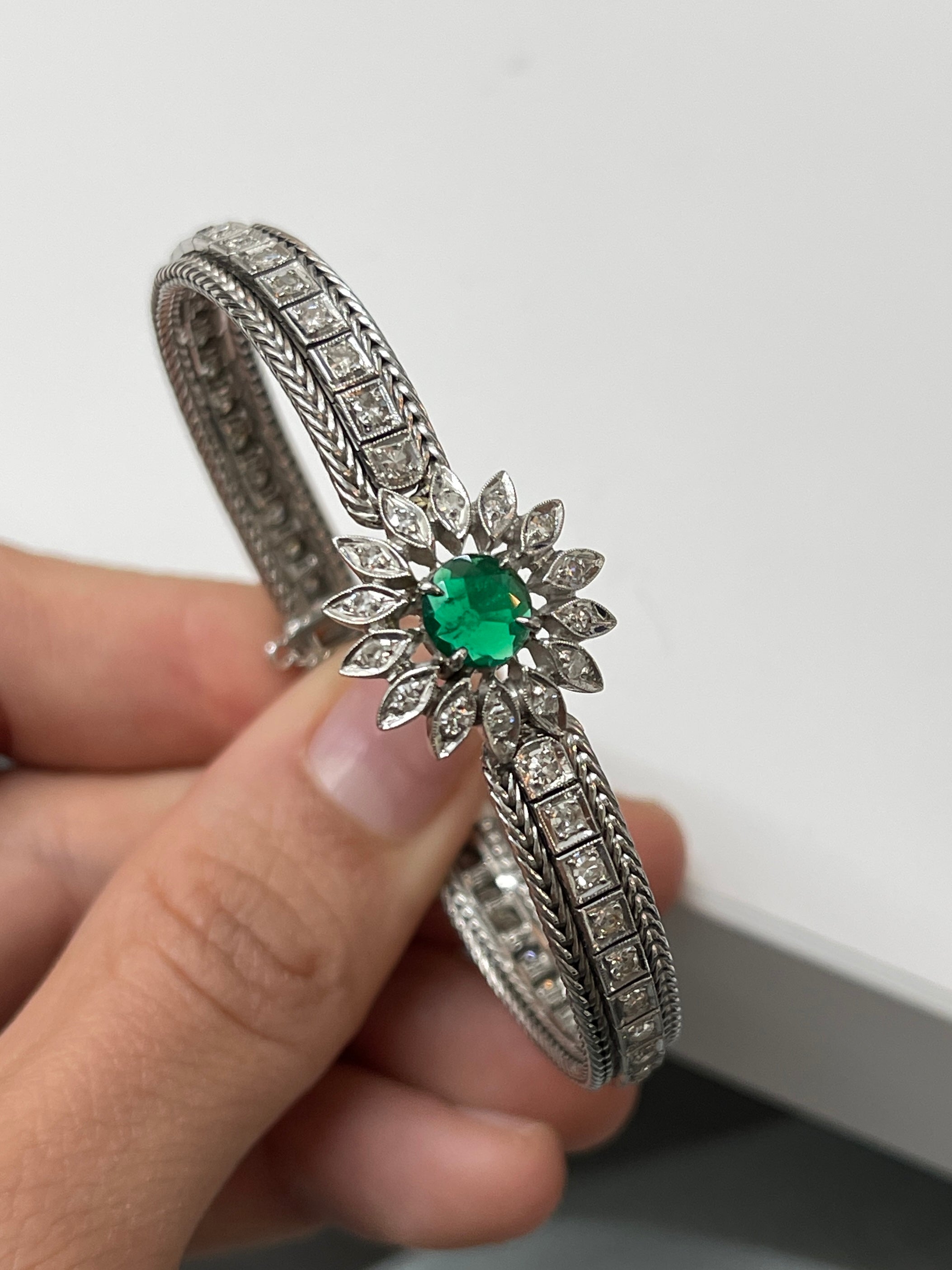 Vintage 1920s Colombian emerald and diamond floral bangle bracelet in 14K white gold with intricate milgrain details