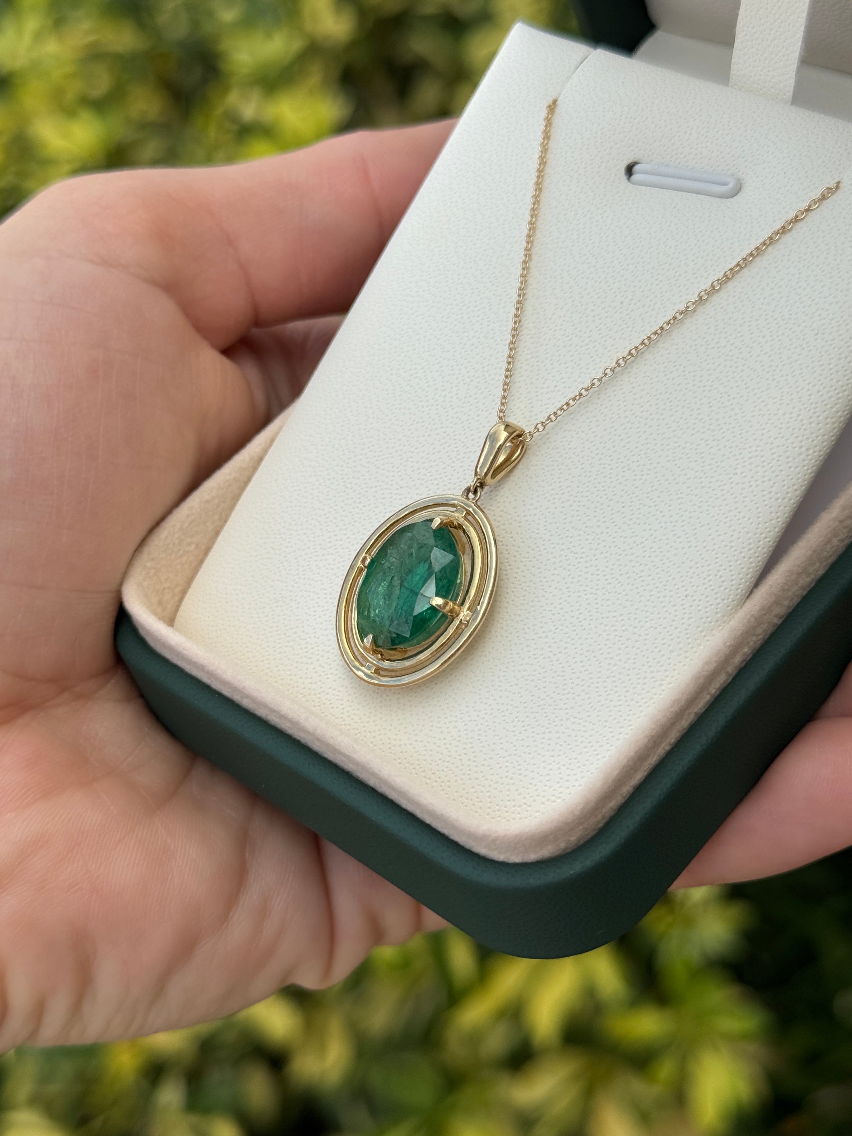 Ciondolo solitario con smeraldo ovale da 5,71 carati, con doppia cornice a corona in oro giallo 14 carati, caratterizzato da una montatura flottante a quattro griffe.