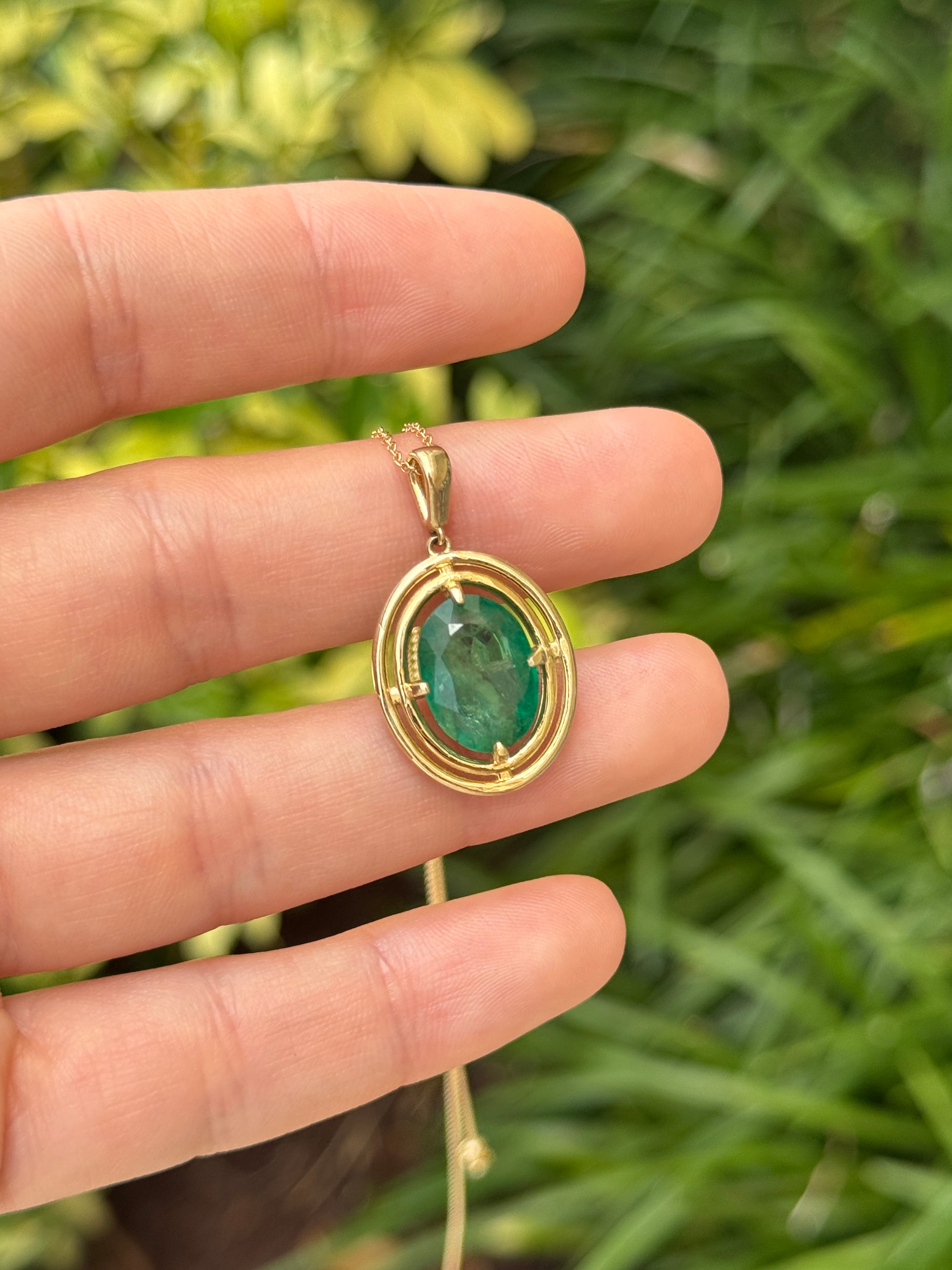 Ciondolo solitario con smeraldo ovale da 5,71 carati con doppio halo in oro giallo 14 carati, caratterizzato da una montatura flottante a quattro griffe.