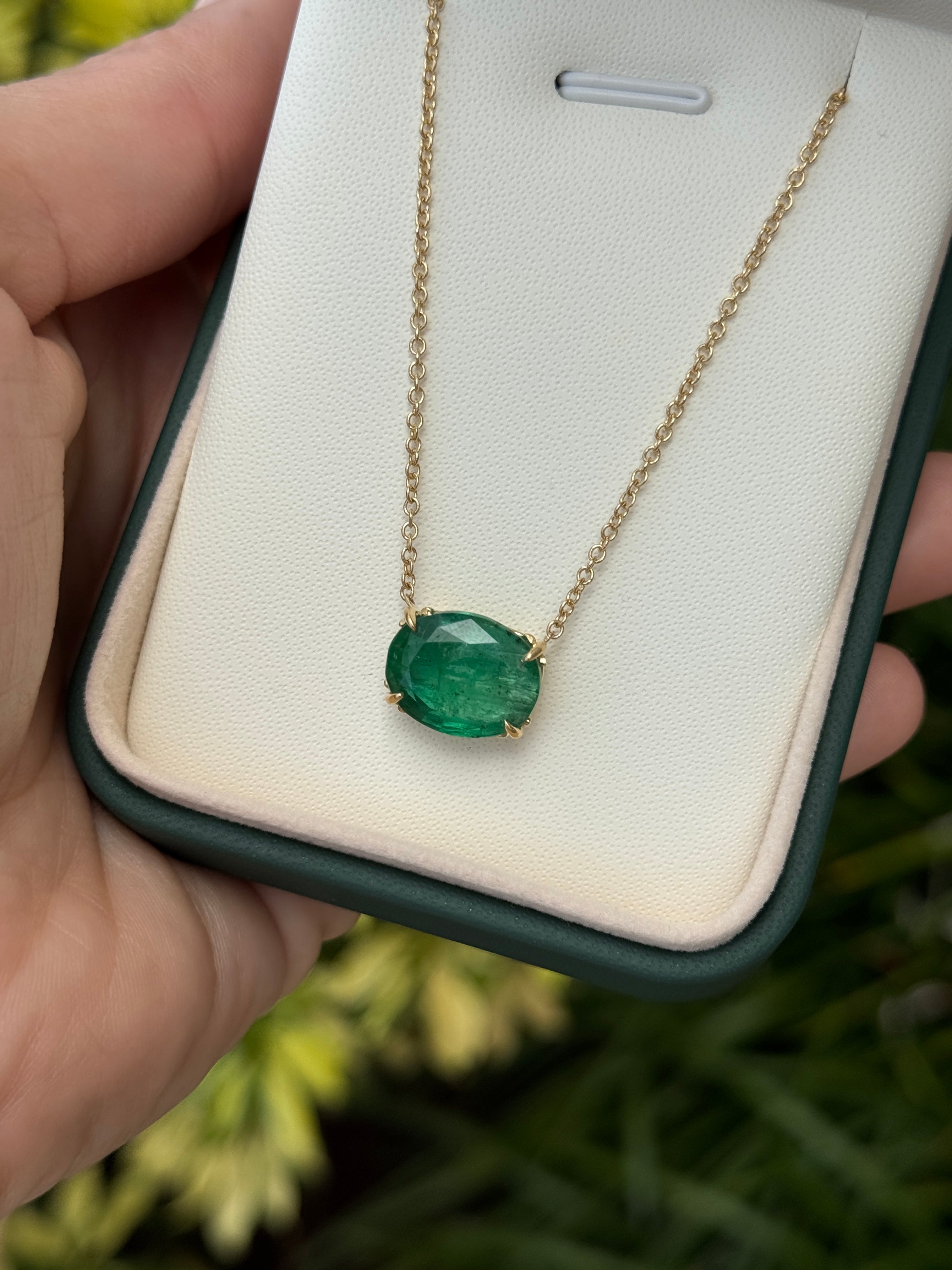 18K gold emerald necklace with oval station pendant featuring Fleur De Lis design, 6.80 carats of natural Colombian emeralds.