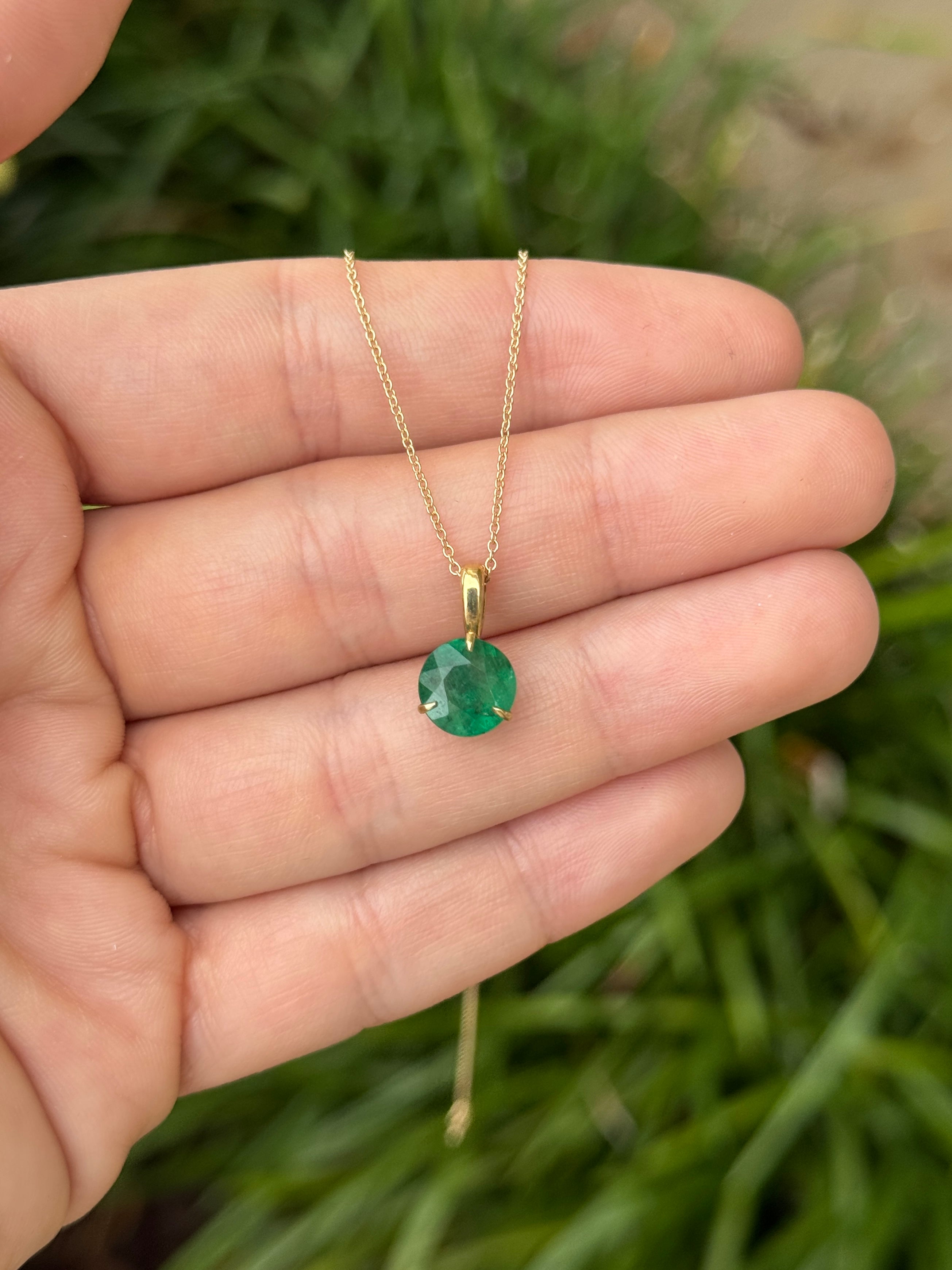 14K gold emerald solitaire necklace featuring a 1.66ct round emerald gemstone held by a three-prong setting.