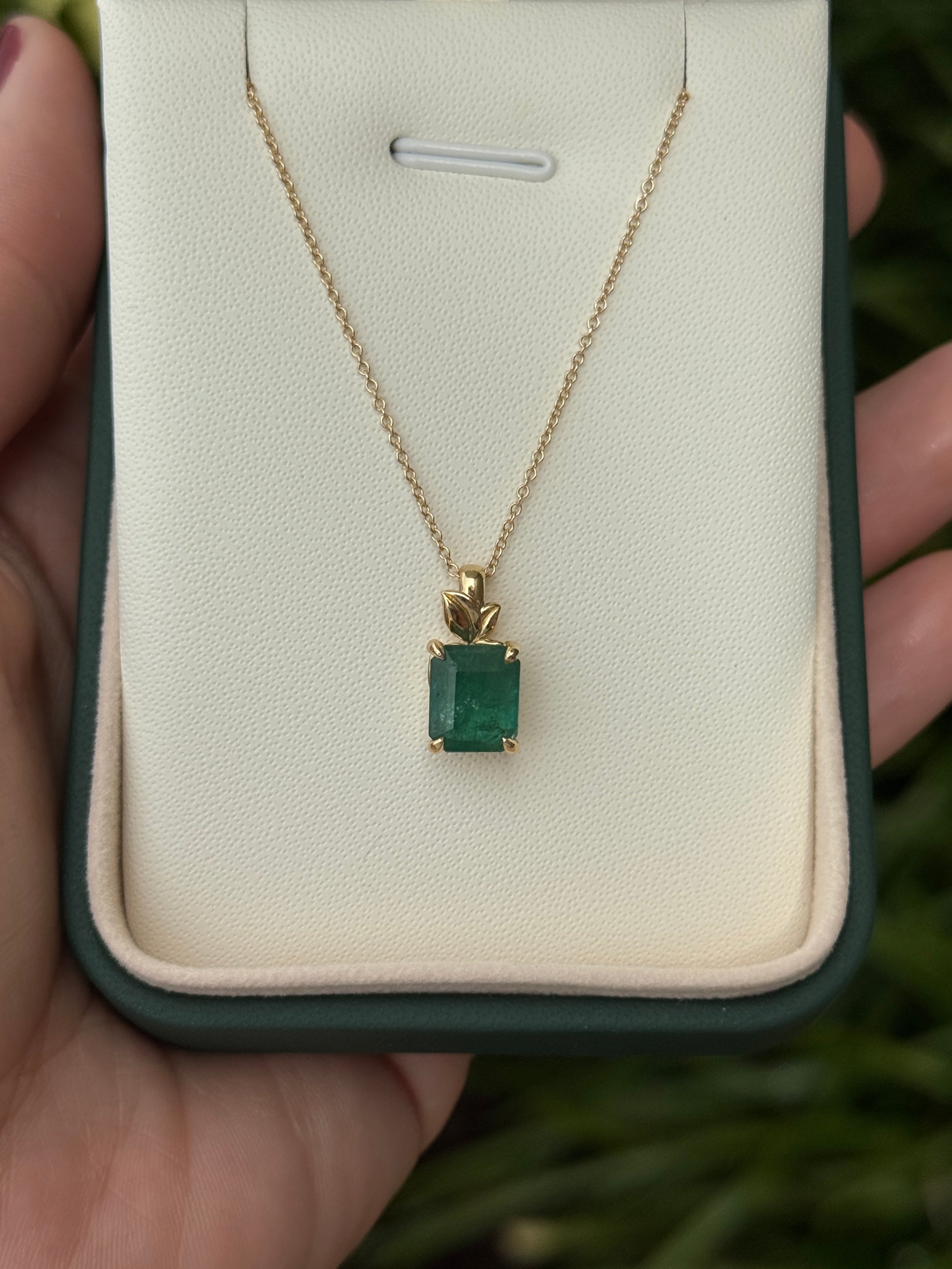 Emerald cut 2.52 carat emerald pendant with leaf design and 14K gold chain, showcasing a nature-inspired emerald necklace.