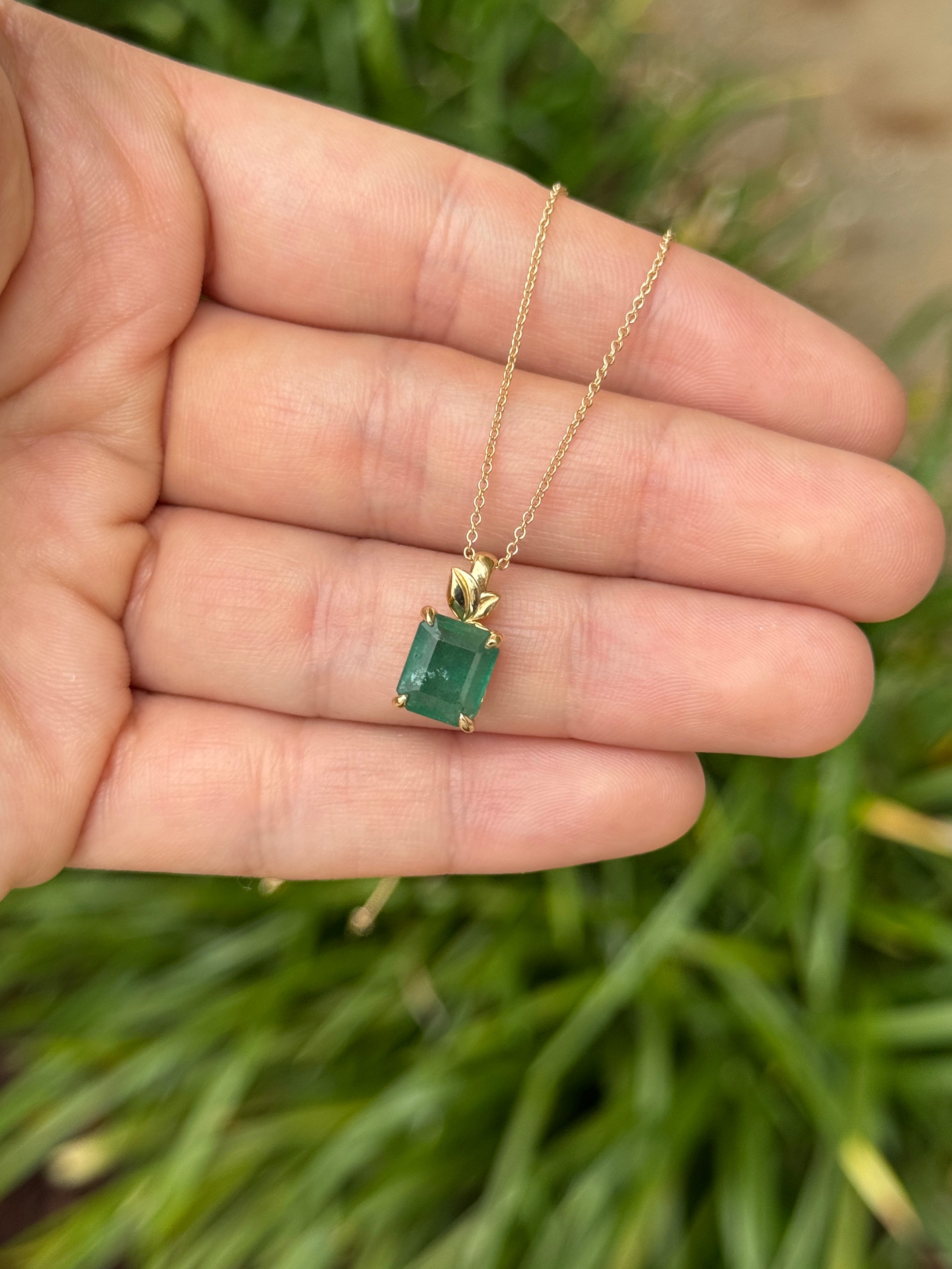 Emerald cut emerald pendant on gold chain with leaf and nature-inspired design, 14K gold necklace by JR Colombian Emeralds.