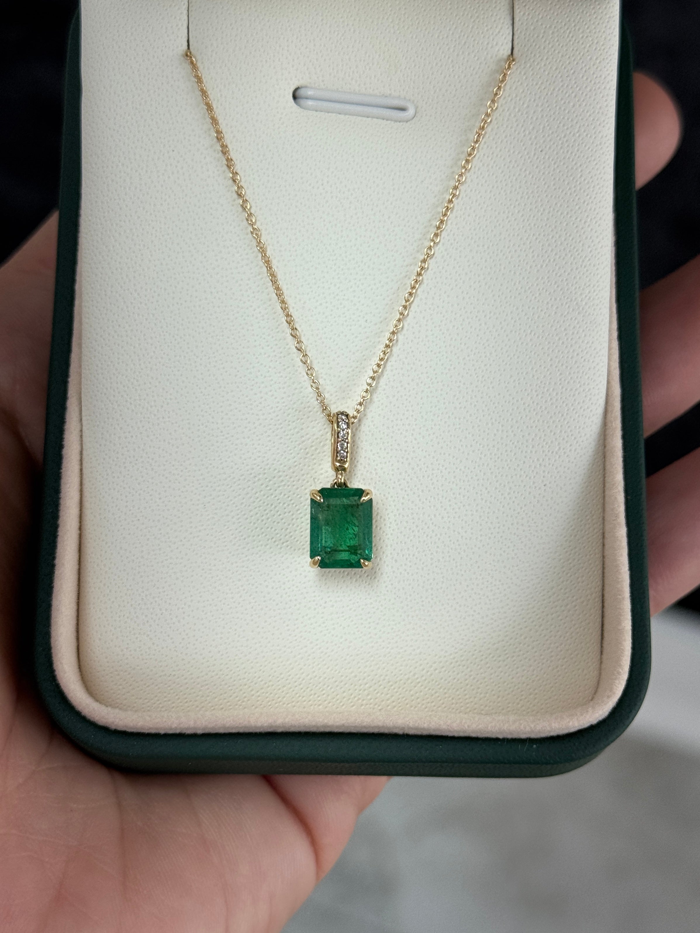 Emerald cut emerald pendant with diamond bail in 14K gold, featuring 1.79 tcw of vibrant Colombian emeralds.