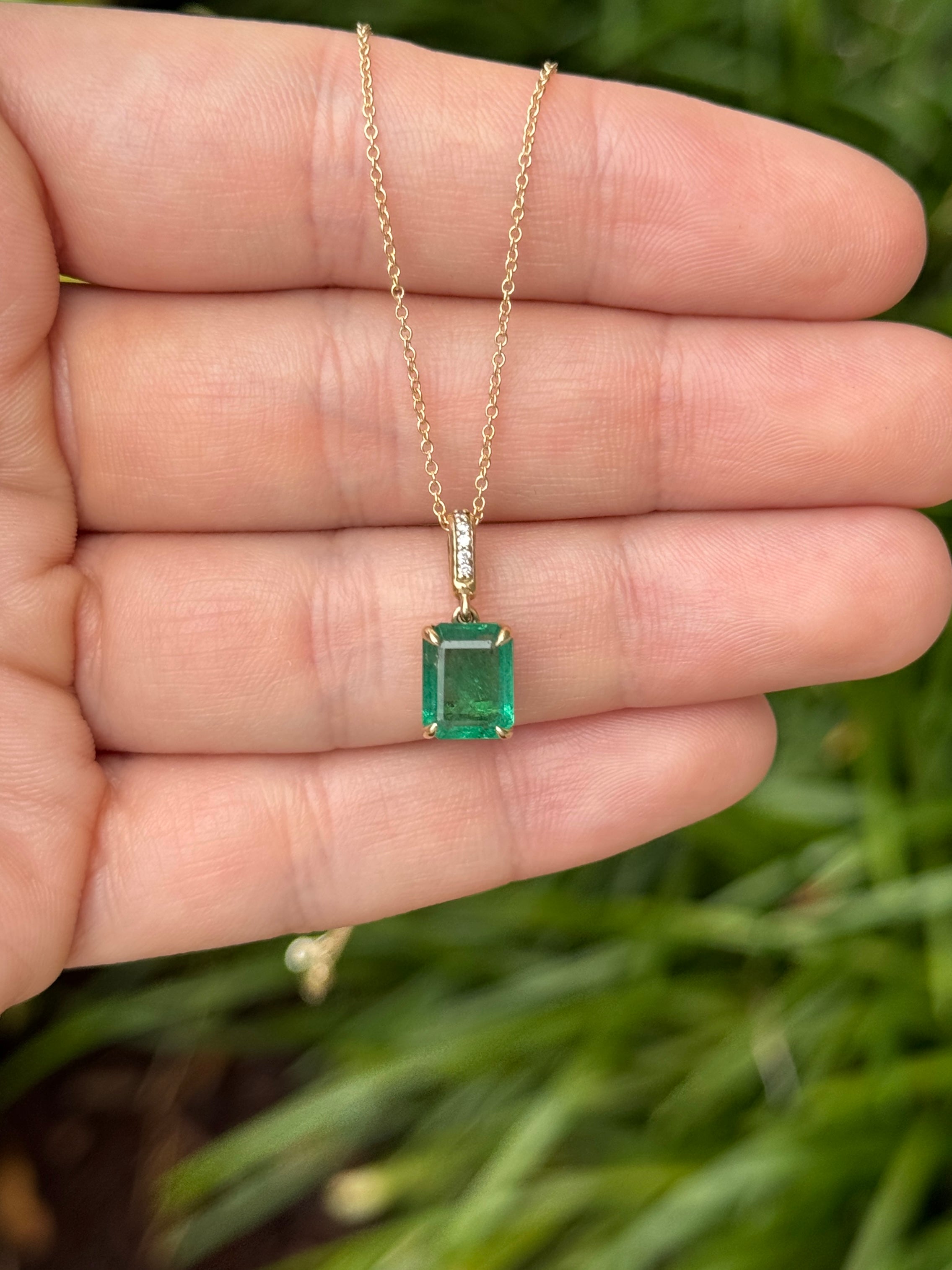 Emerald cut emerald pendant with diamond bail in 14K gold by JR Colombian Emeralds, showcasing a vibrant green gemstone.