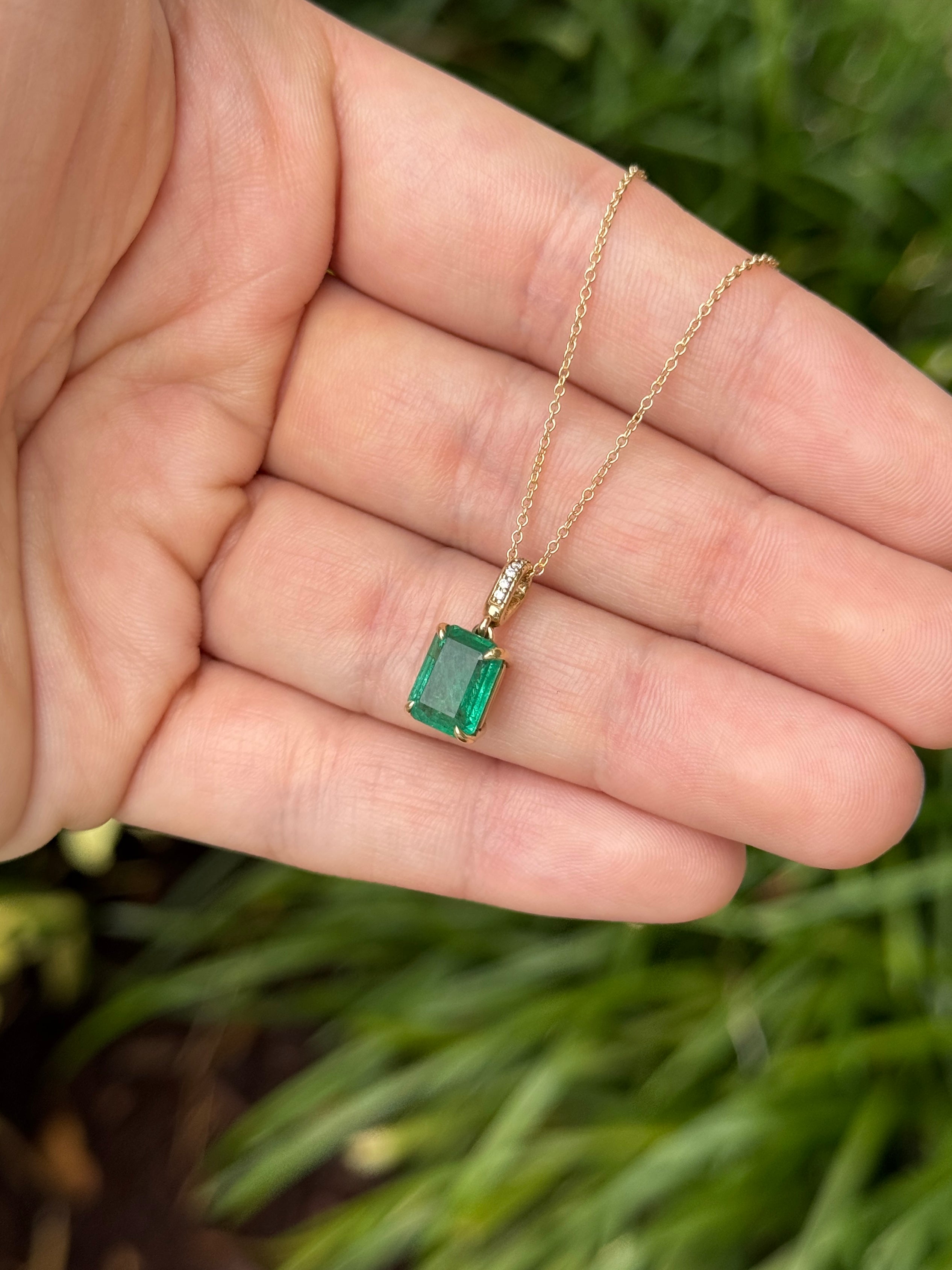 Emerald cut emerald pendant with diamond bail in 14K gold, featuring 1.79 carats of vibrant Colombian emeralds and sparkling diamonds.