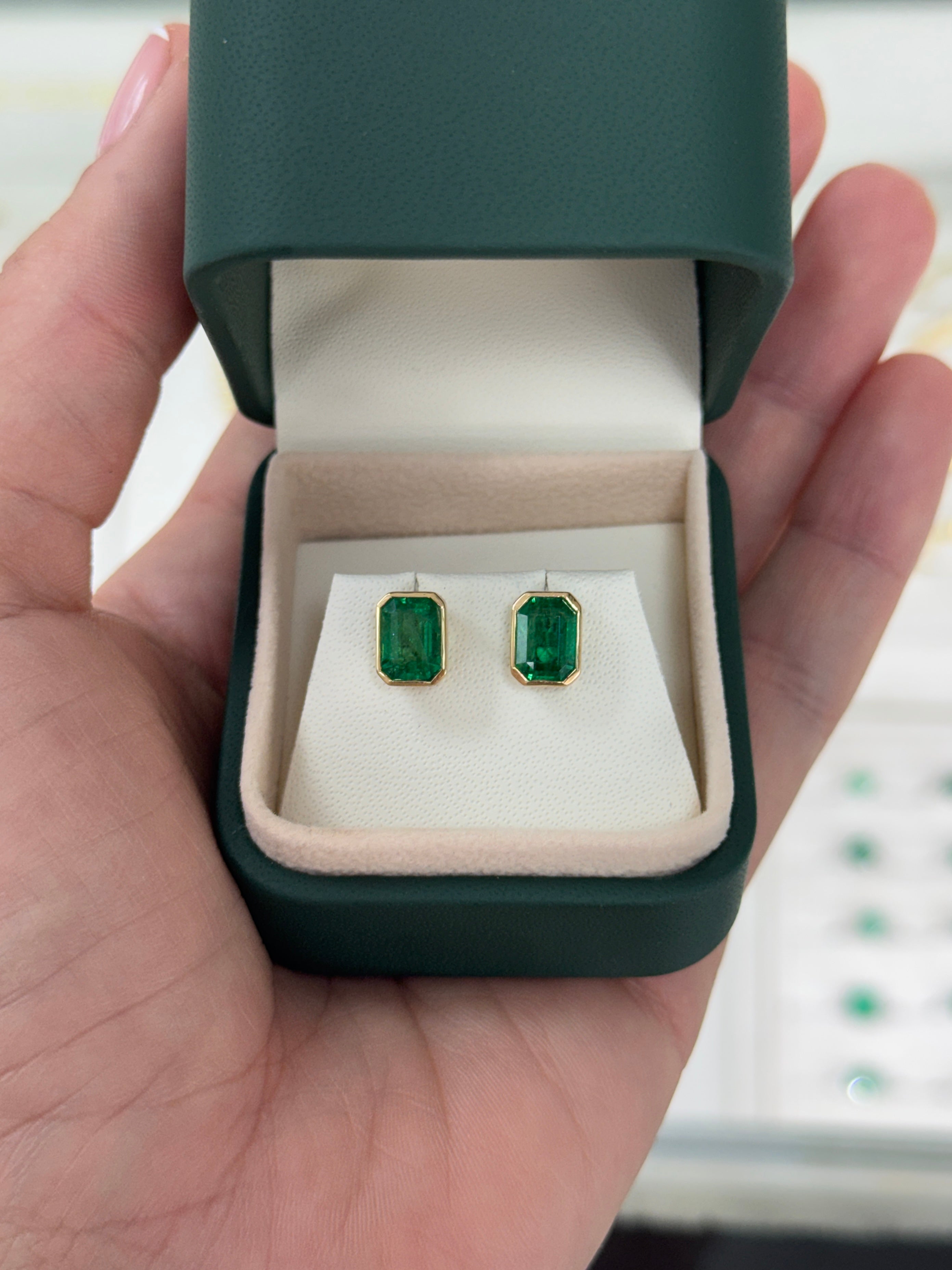 Emerald stud earrings featuring 3.33 carats bezel set in 18K gold by JR Colombian Emeralds, shown with a close-up view of the jewelry.