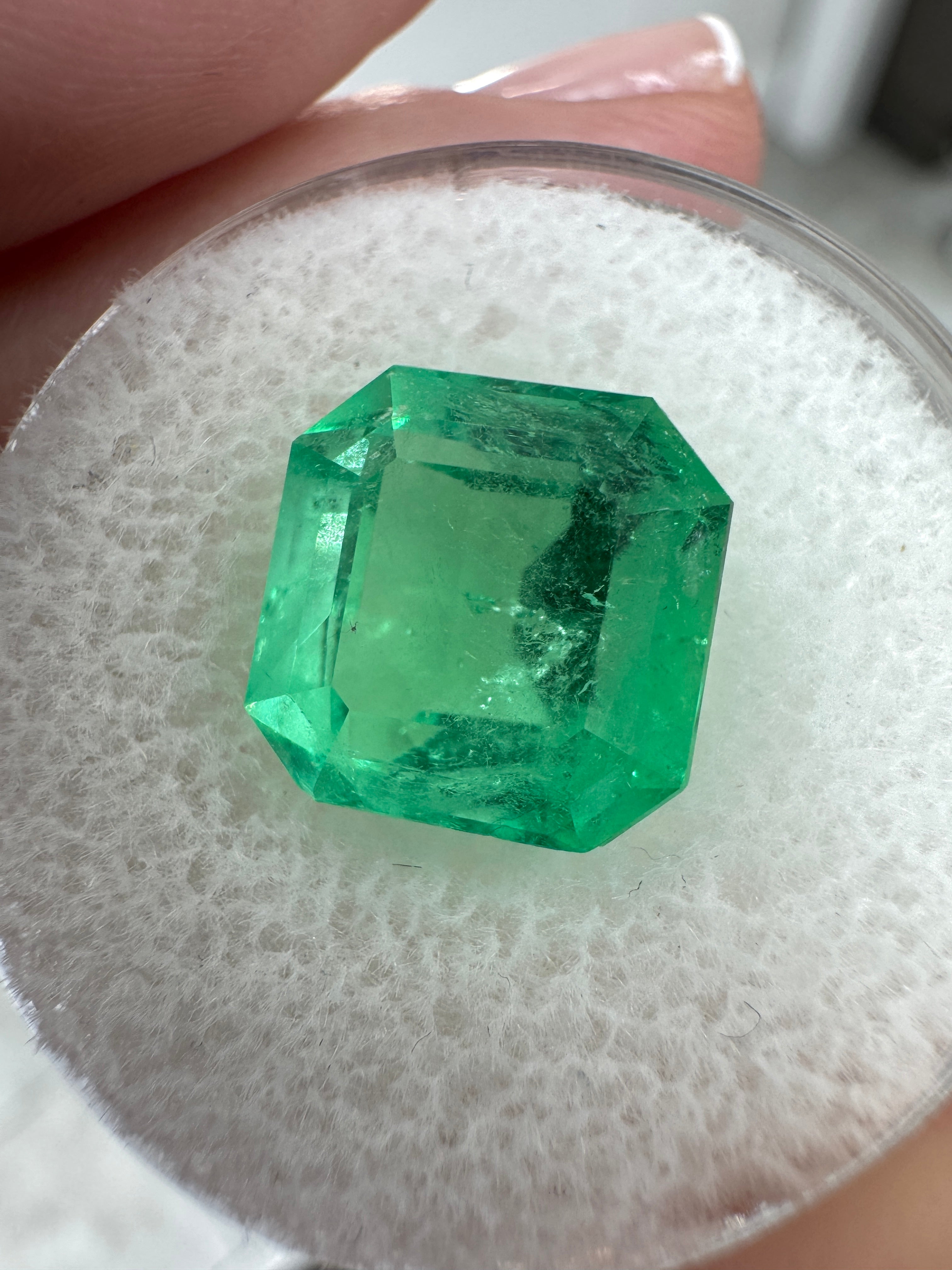 Bright 4.57 carat Colombian emerald Asscher cut with clipped corners, glowing and loose, from JR Colombian Emeralds.