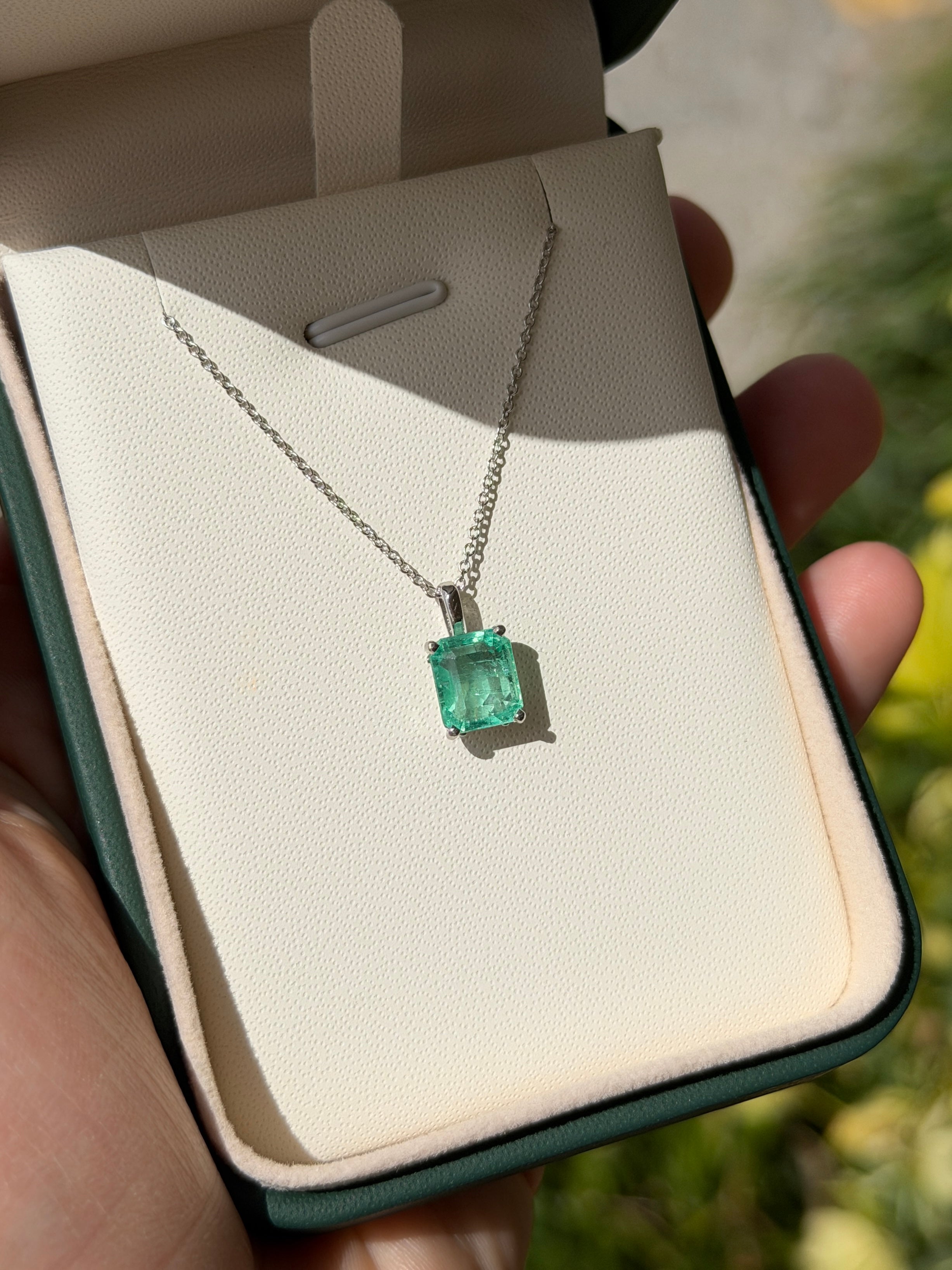 14K white gold Colombian emerald fleur de lis solitaire necklace featuring a 2.20 carat emerald gemstone.