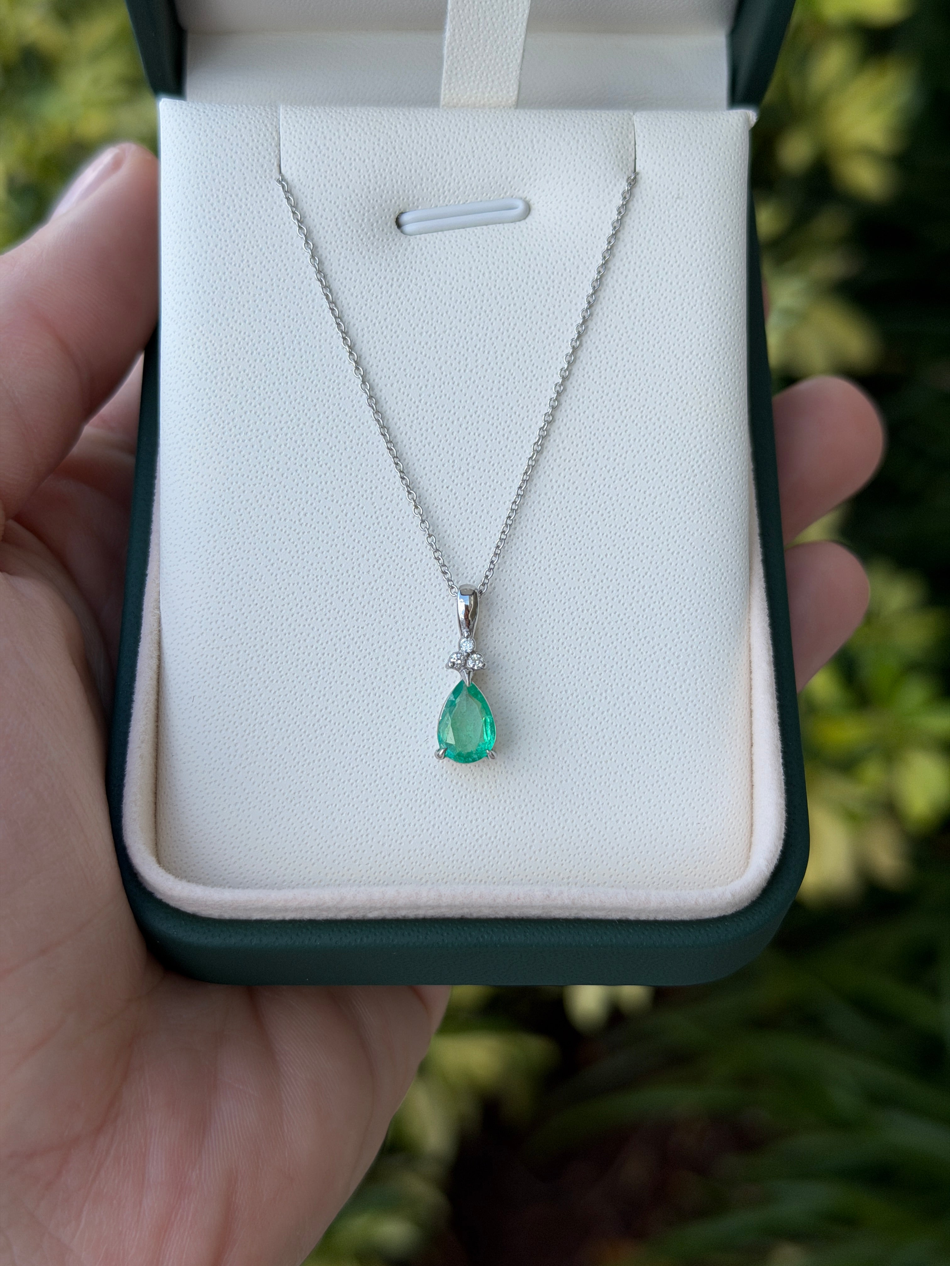 Pear-shaped emerald drop pendant with trefoil diamond cluster in 14K white gold, featuring 1.04tcw emeralds and diamonds.