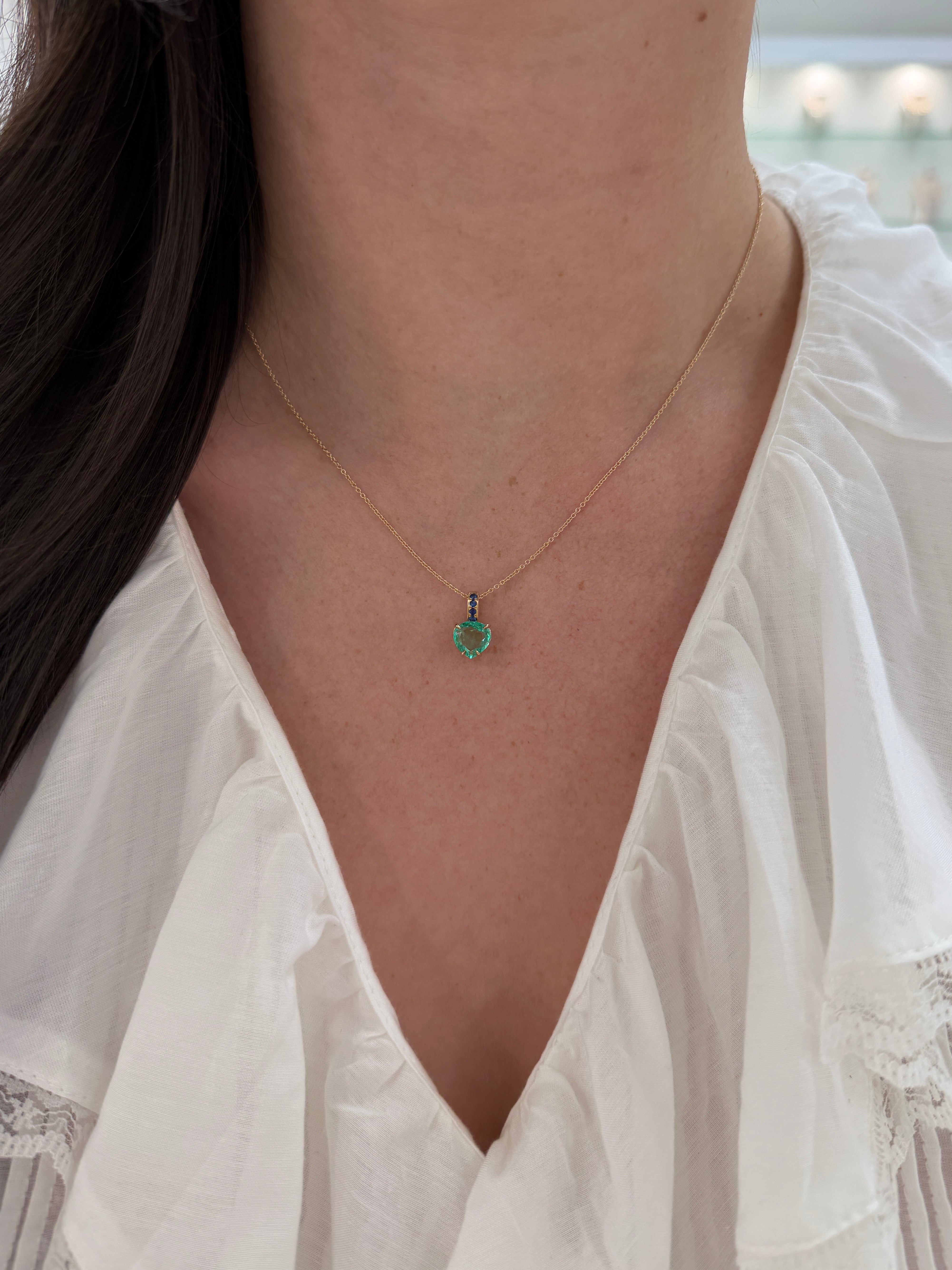 Colombian pear-shaped emerald pendant with blue sapphire bail in 14K gold, featuring a heart-shaped design by JR Colombian Emeralds.