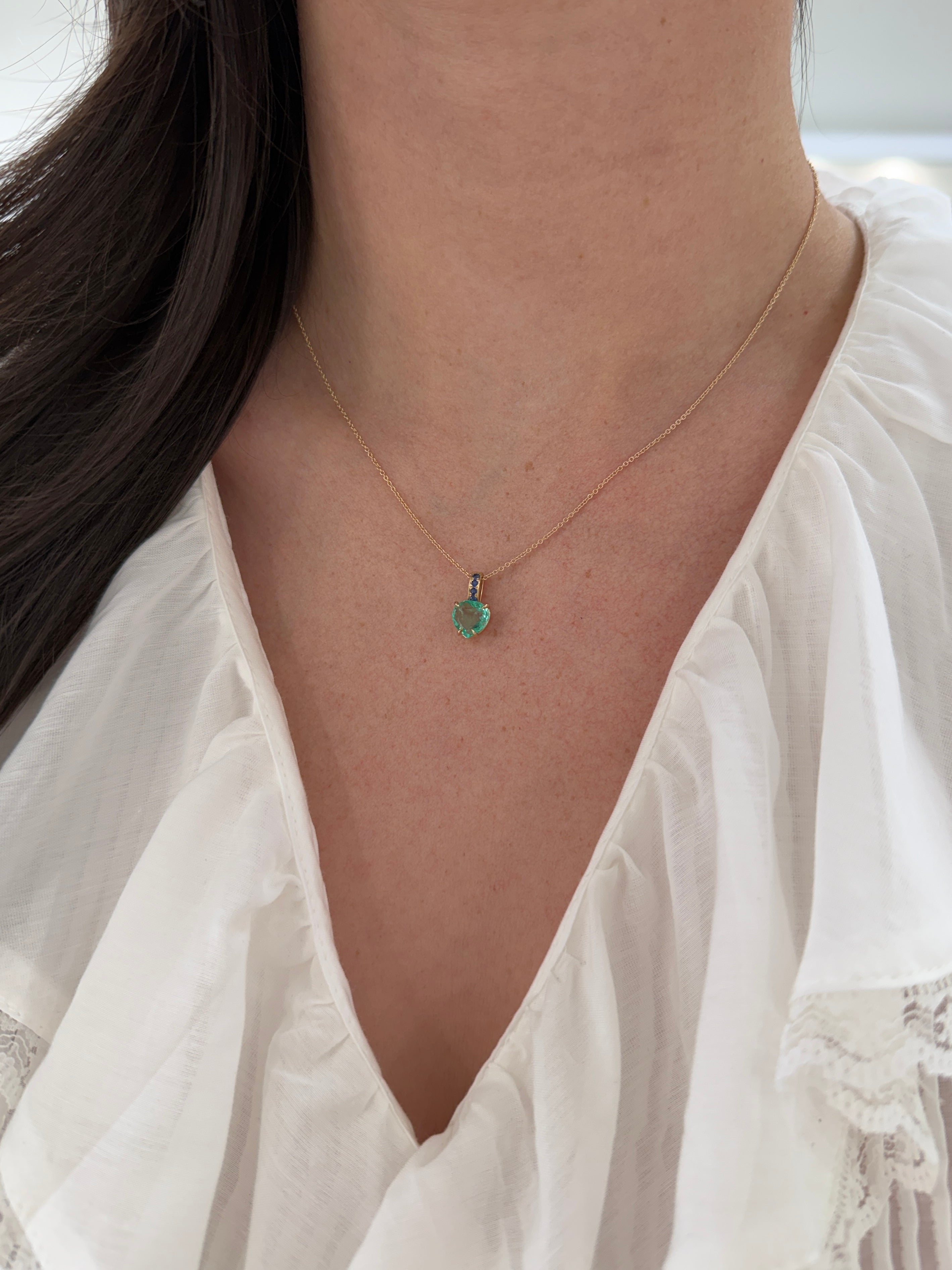 Colombian pear-shaped emerald pendant with blue sapphire bail and 14K gold heart design, jewelry by JR Colombian Emeralds.