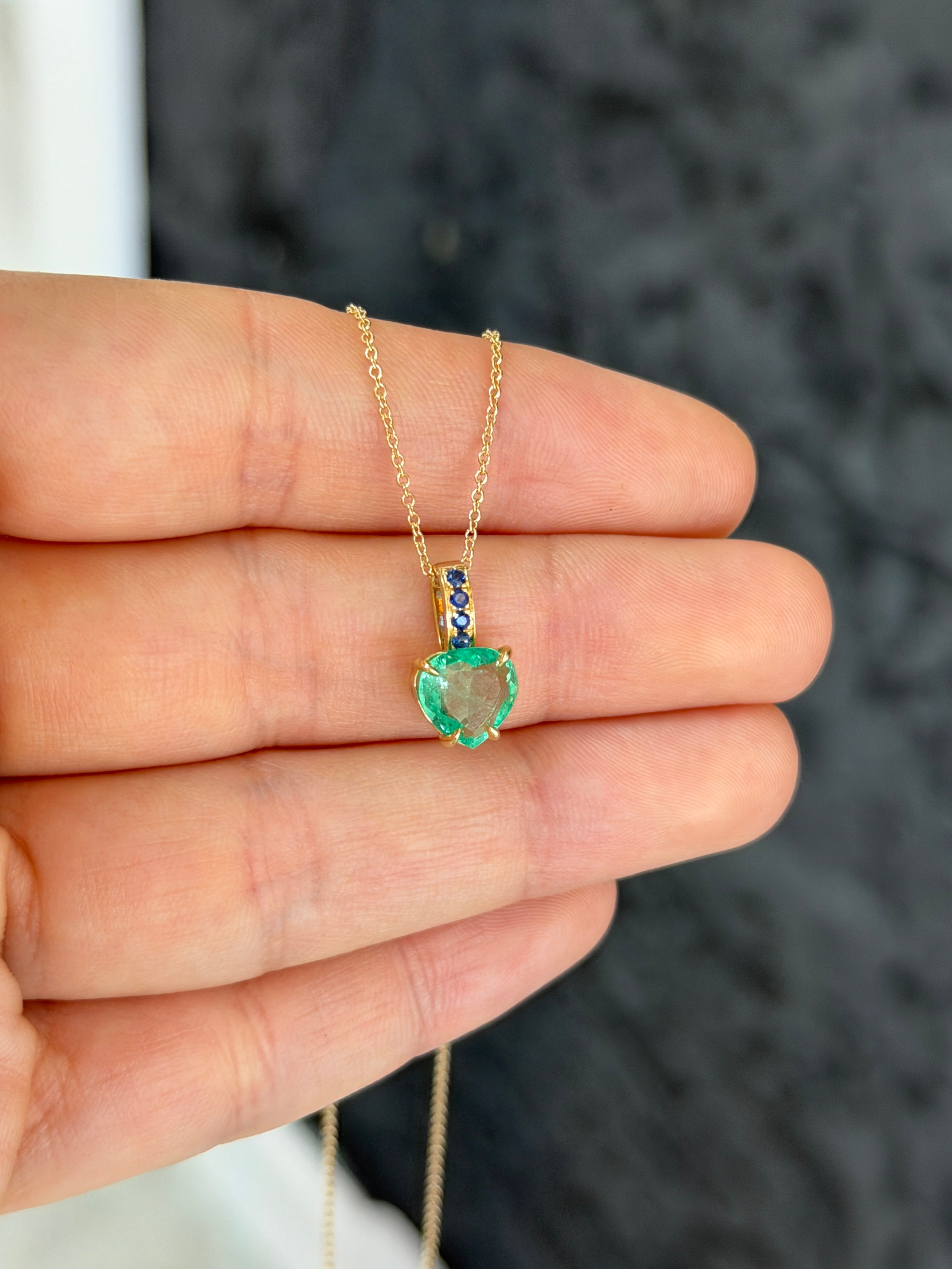 Colombian pear-shaped emerald pendant with blue sapphire bail in 14K gold, featuring a heart-shaped design by JR Colombian Emeralds.