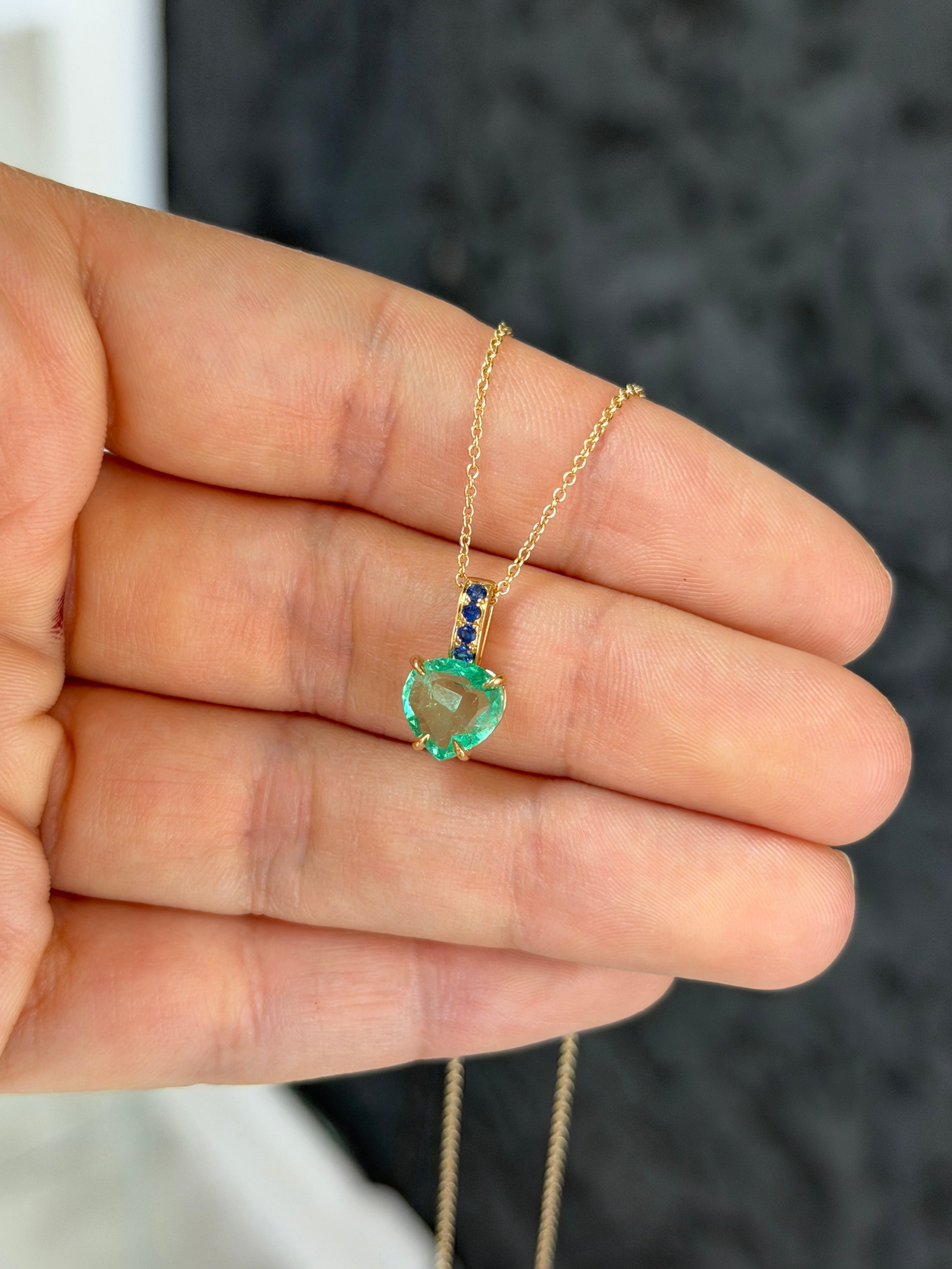 Colombian pear-shaped emerald pendant with blue sapphire bail in 14K gold, featuring a heart-shaped design by JR Colombian Emeralds.