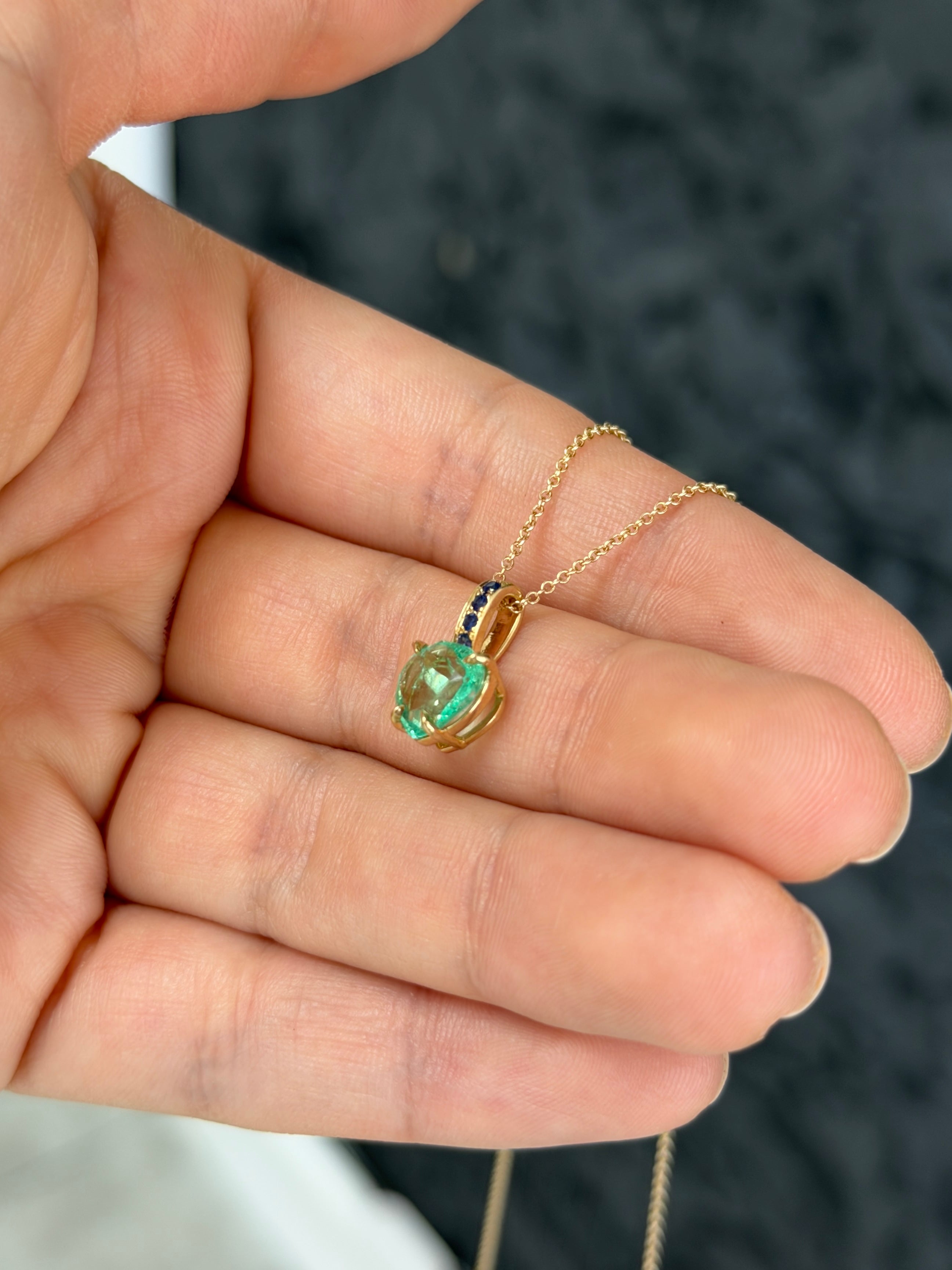 14K gold Colombian pear emerald pendant with blue sapphire bail, featuring a 1.09ctw heart-shaped emerald and sapphire accents.