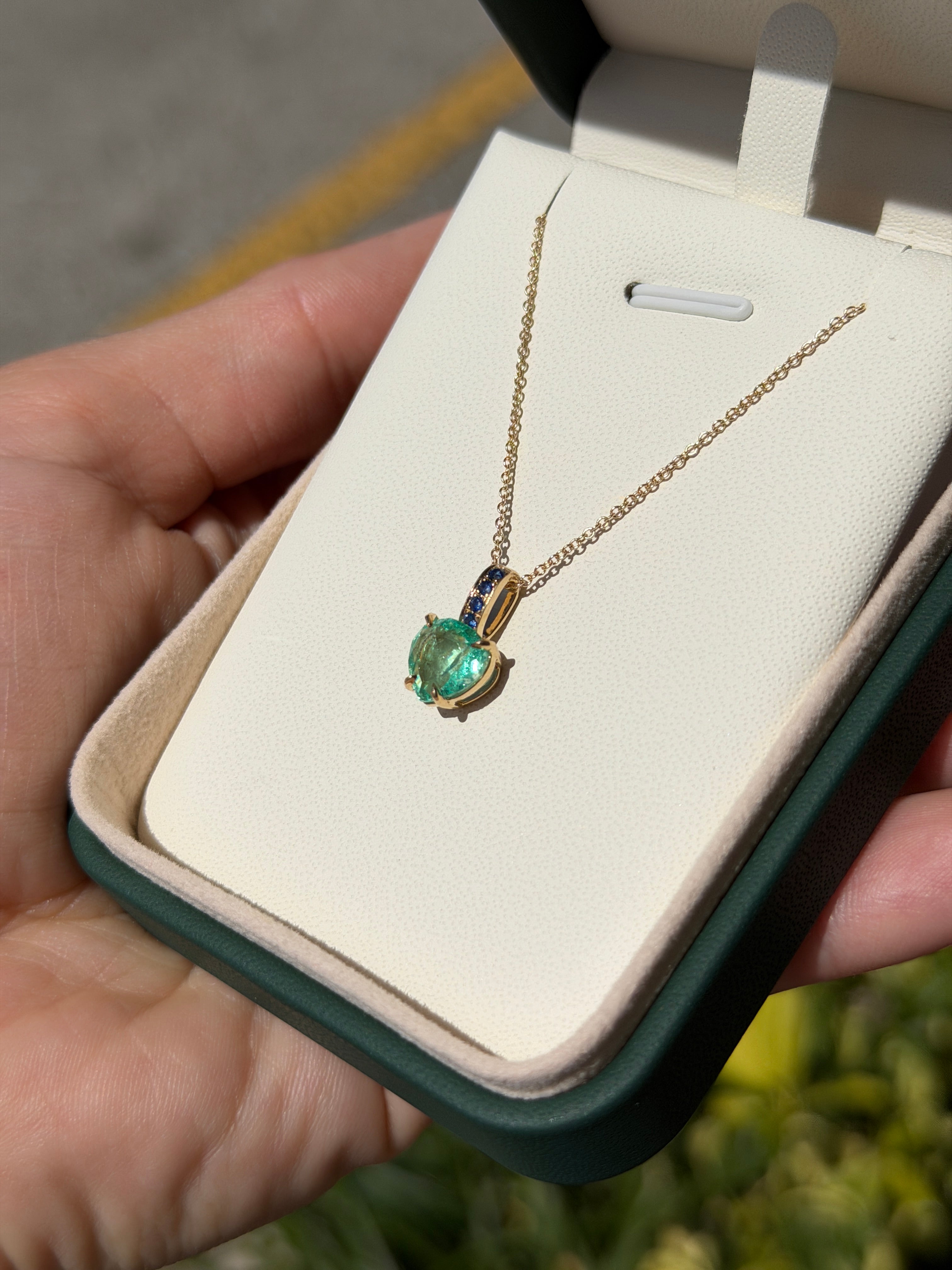 Colombian pear-shaped emerald pendant with blue sapphire bail in 14K gold, featuring a heart-shaped design by JR Colombian Emeralds