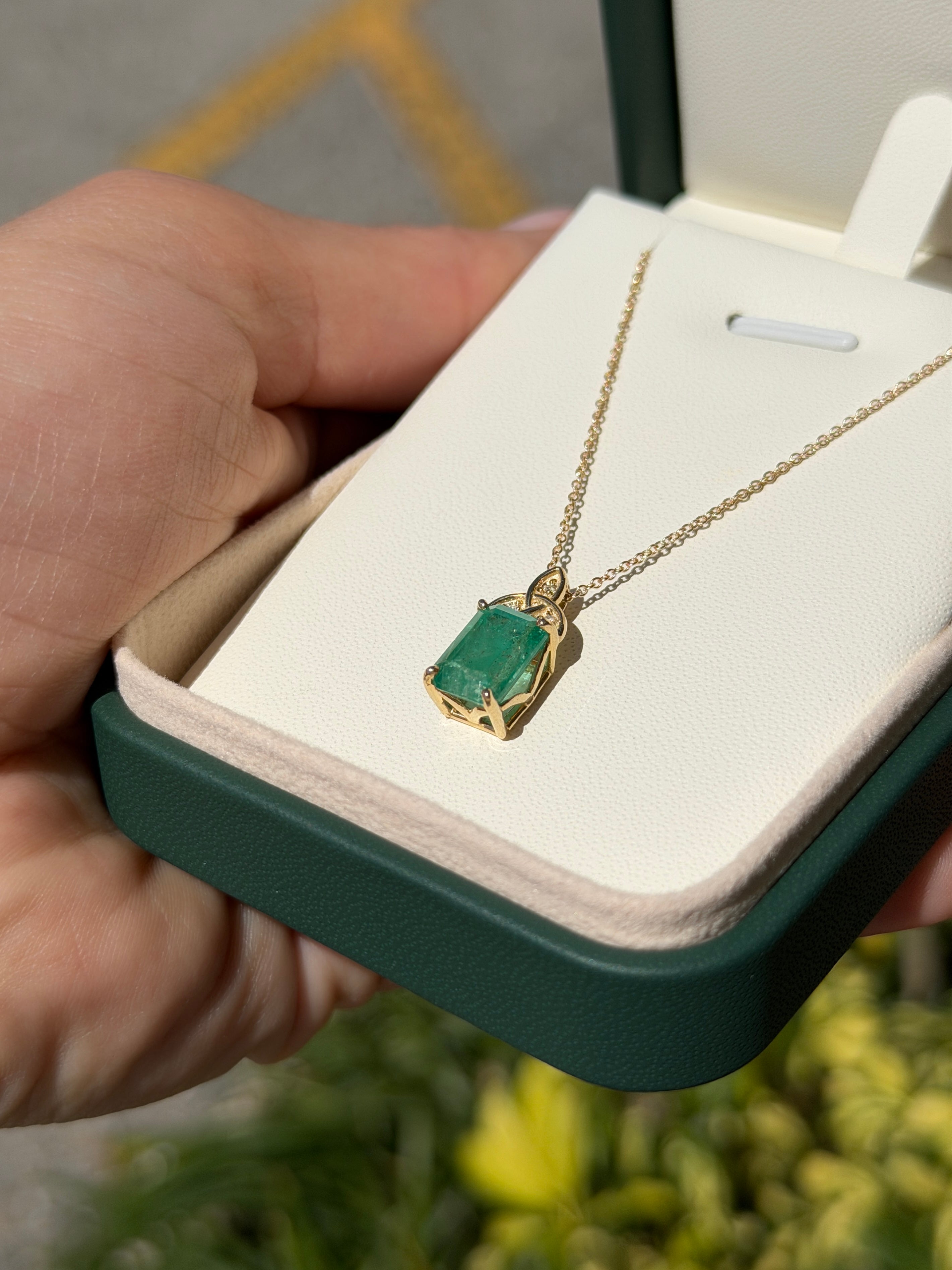 14K yellow gold Trinity knot emerald solitaire necklace featuring a central emerald gemstone with intricate gold detailing.