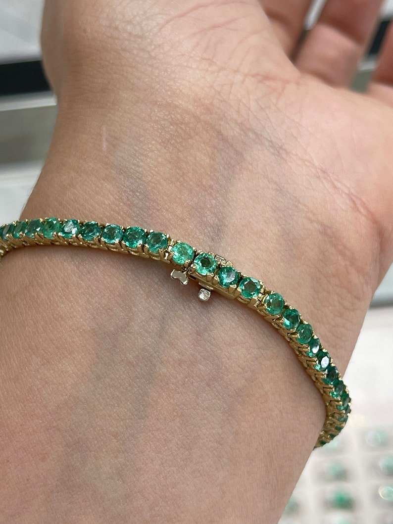 Unisex tennis bracelet featuring medium dark green round cut emeralds and 14K gold from Colombian Emerald brand.