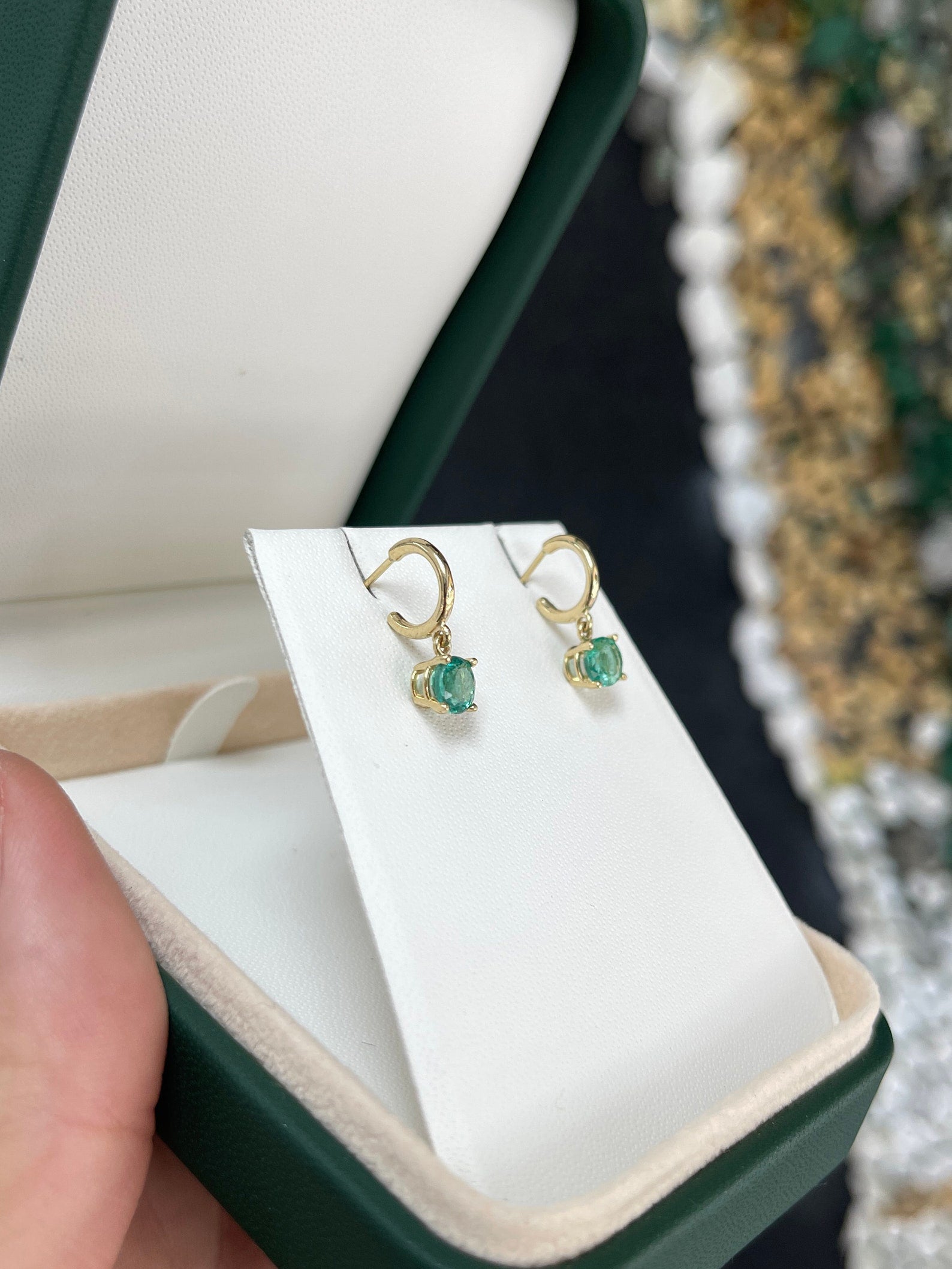 Medium dark green emerald round cut huggie hoop earrings in 14K gold featuring four prongs, from Colombian Emerald.