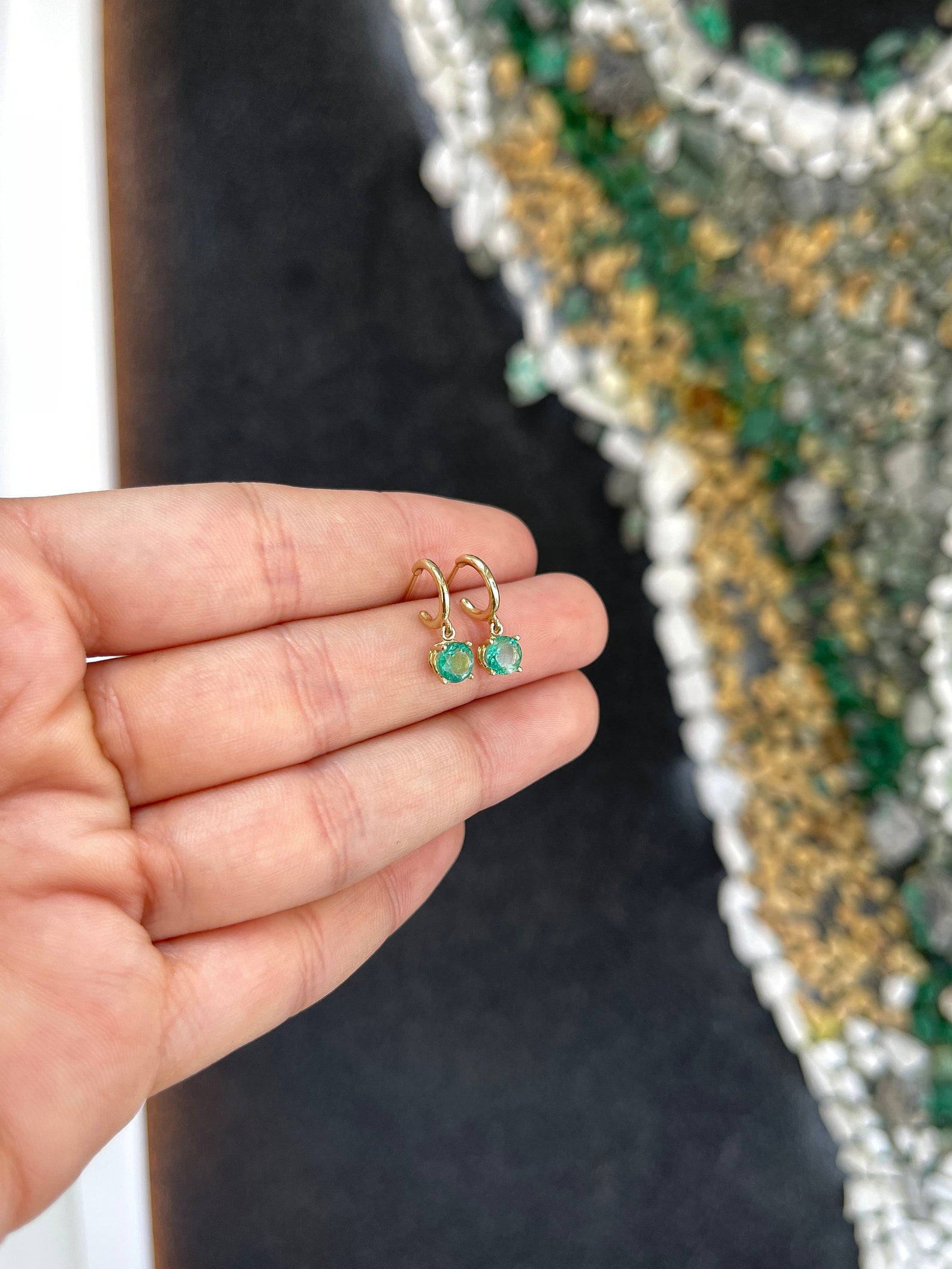 Medium dark green emerald round cut hoop earrings with four prongs in 14K gold, featuring Colombian Emerald branding.