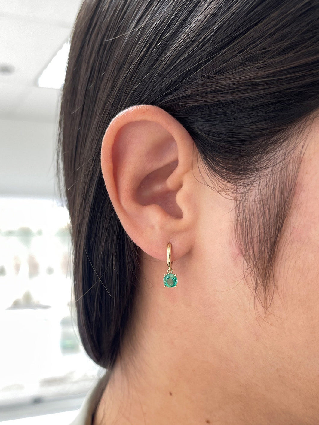 Medium dark green emerald round cut hoop earrings with four prongs, 14K gold, from Colombian Emerald brand.