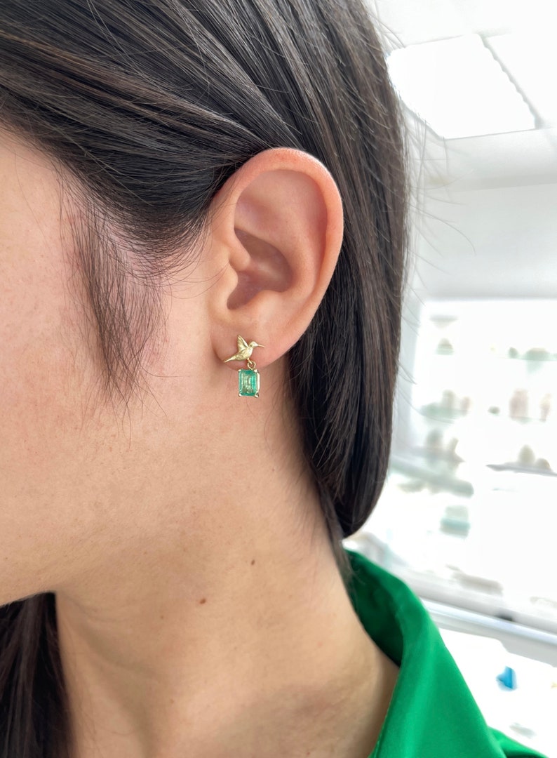 14K gold hummingbird dangle earrings with natural emeralds, featuring 1.90 carats total weight, by Colombian Emerald.