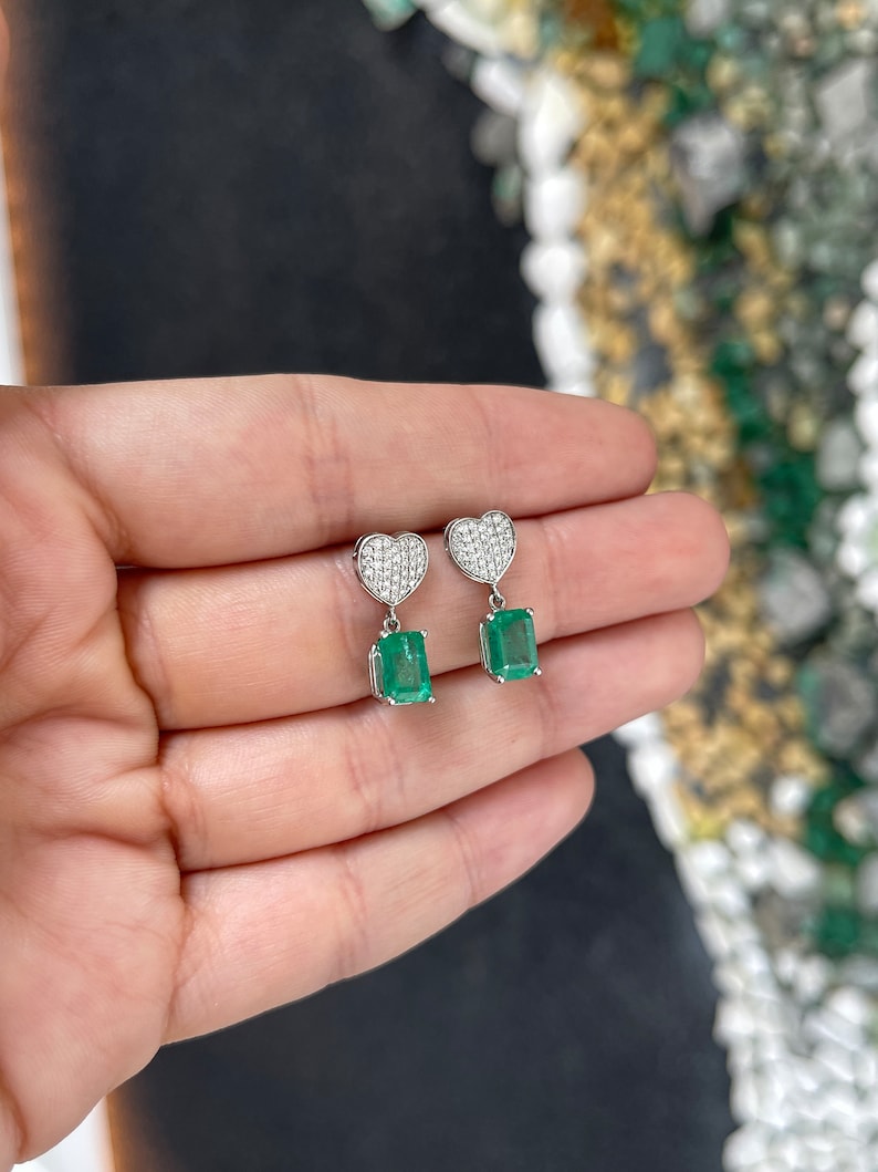 Colombian Emerald and diamond heart cluster dangle earrings in 14K yellow gold with 3.20tcw green emeralds and sparkling diamonds.