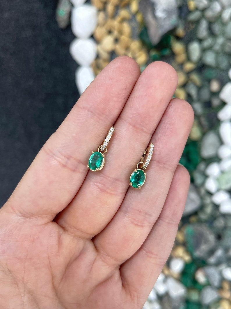 Colombian Emerald 2.0tcw green oval cut earrings with diamond accents in 14K gold dangle style, showcasing lush gemstones.
