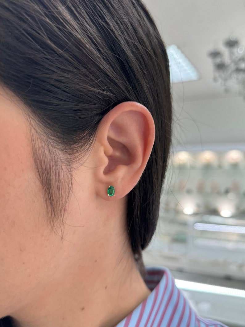 Colombian Emerald 0.80tcw 14K green petite oval cut four-prong children stud earrings, showcasing vibrant emerald gemstones.