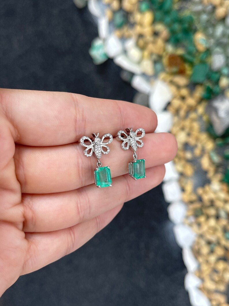 Colombian Emerald 14K gold butterfly dangle earrings with medium green emeralds and pave diamonds, showcasing elegant jewelry design.