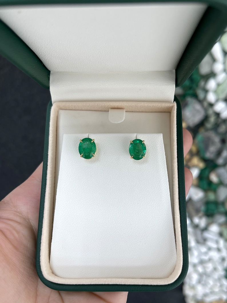 Colombian Emerald 18K gold stud earrings featuring vivid dark green oval cut emeralds with four-prong claw settings.