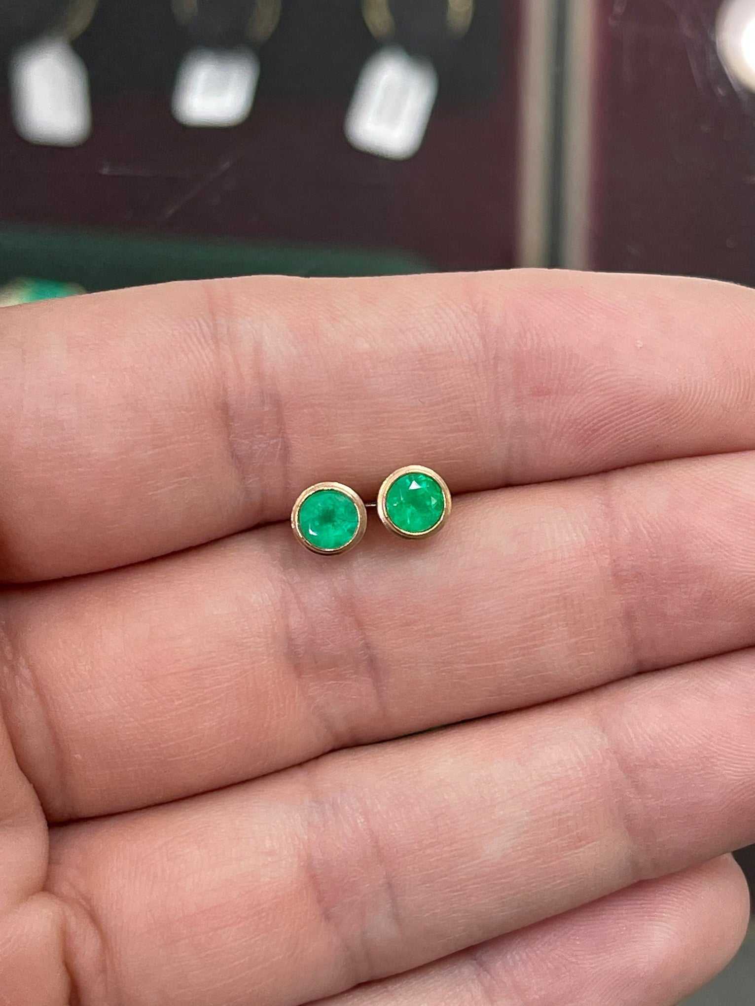 Rich green emerald stud earrings with round cut diamonds set in 14K yellow gold from Colombian Emerald.