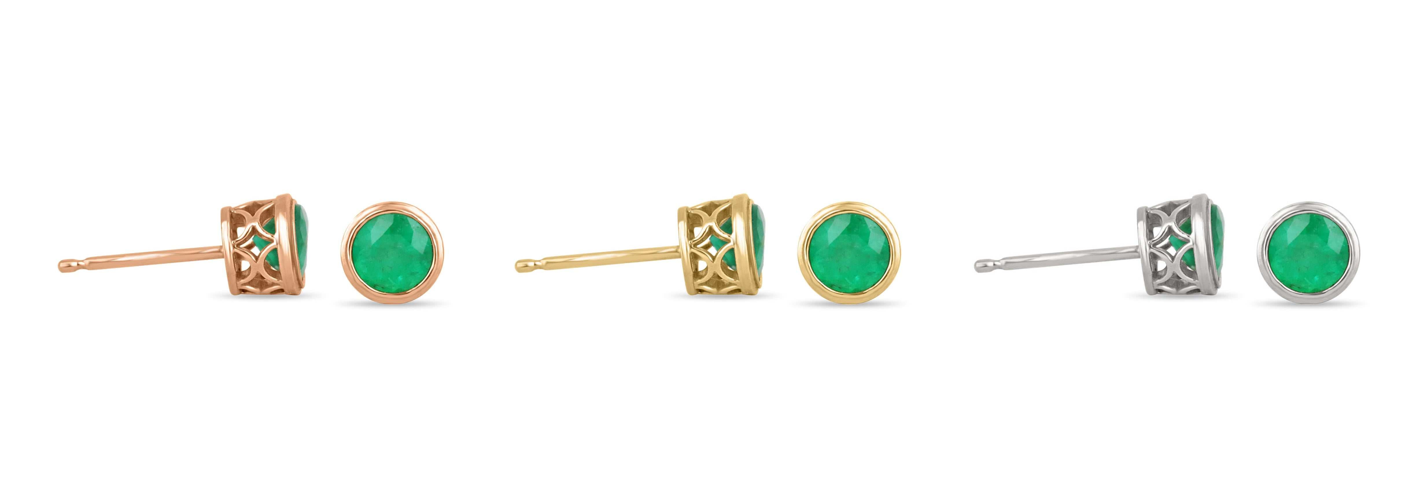 Rich green emerald round cut bezel set stud earrings in 14K yellow gold, featuring 1.40tcw Colombian emeralds.