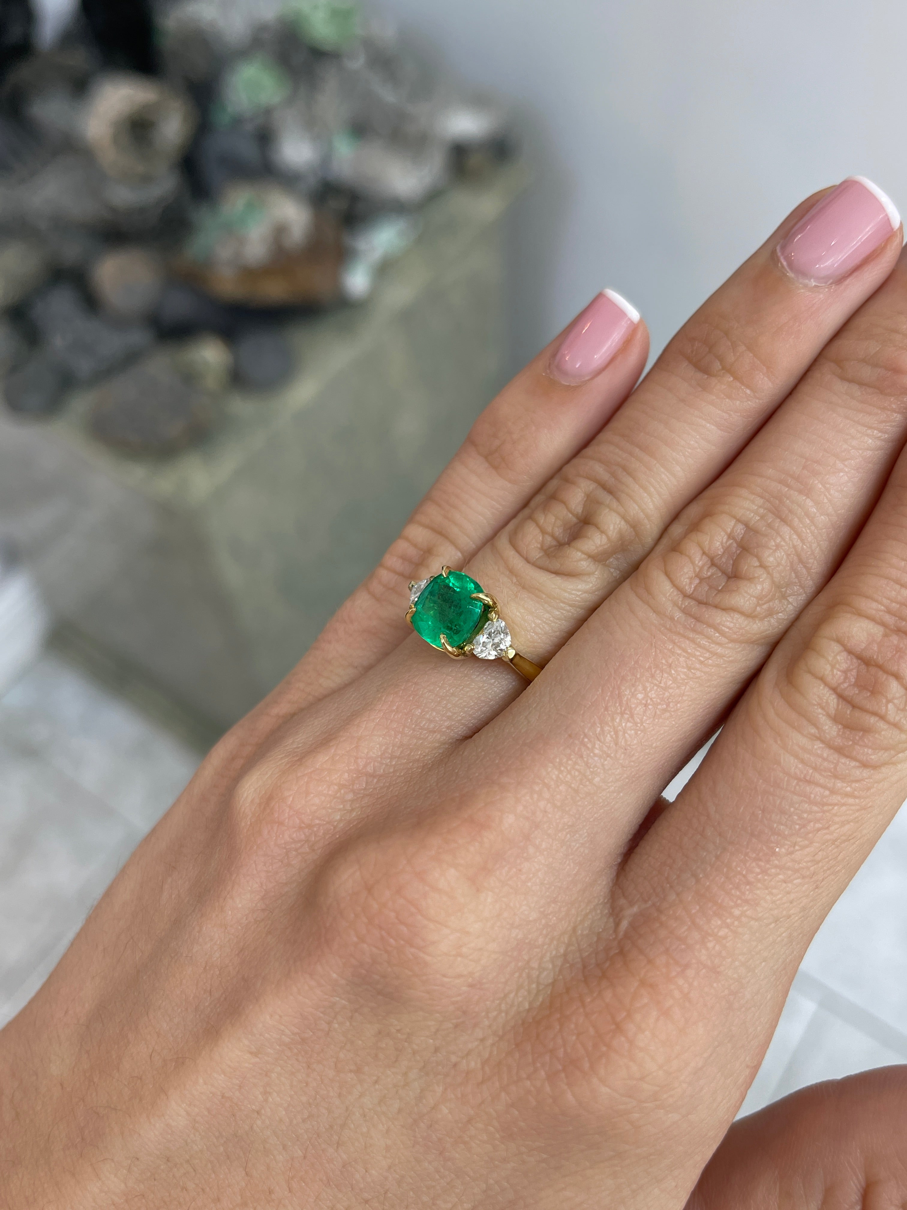 Vivid Colombian cushion emerald and heart-shaped diamond engagement ring in 18K gold, showcasing intricate design and sparkling gemstones.