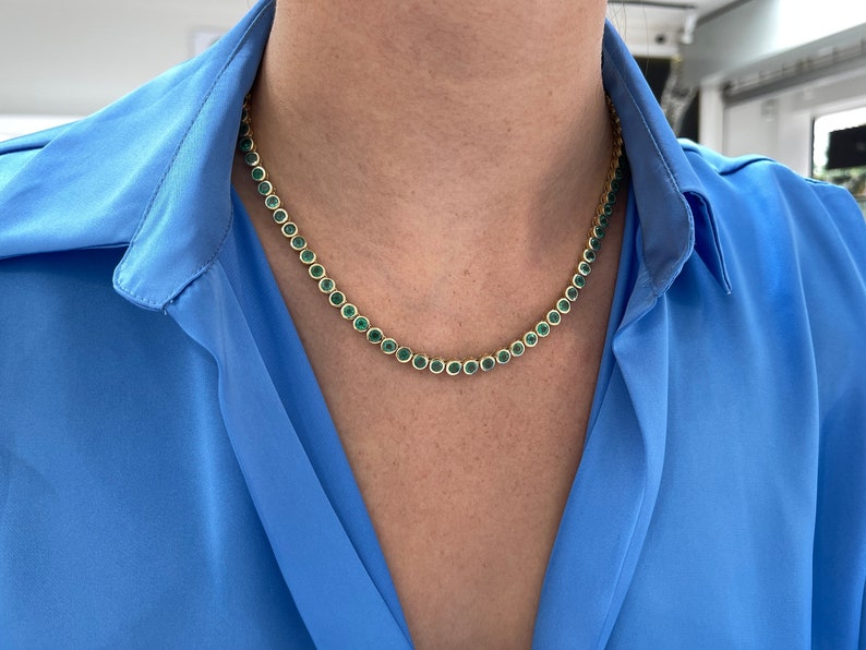 14K natural green emerald tennis necklace with round cut stones totaling 25.50 carats, bezel-set from Colombian Emerald brand.