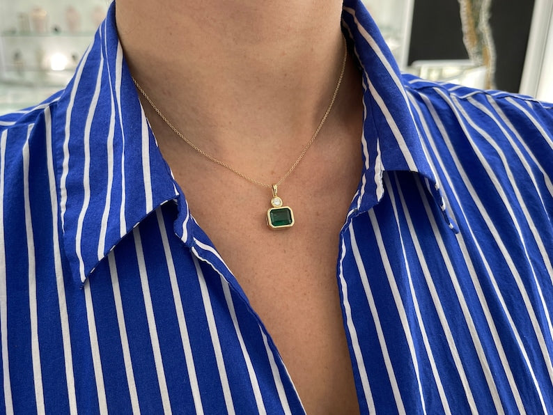 Lush dark green Colombian emerald pendant with brilliant round cut diamonds, 14K gold setting, and east-to-west design.