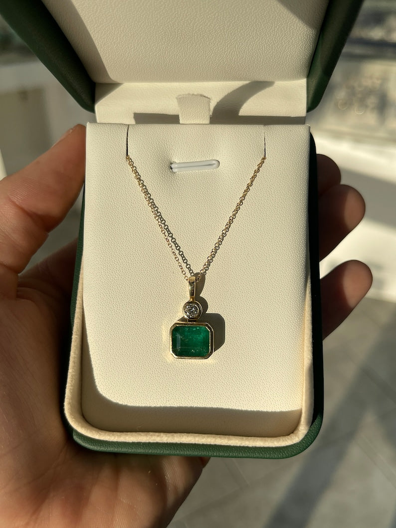 Dark green emerald pendant with round cut diamonds, 14K gold setting, featuring a Colombian emerald and east-to-west design.