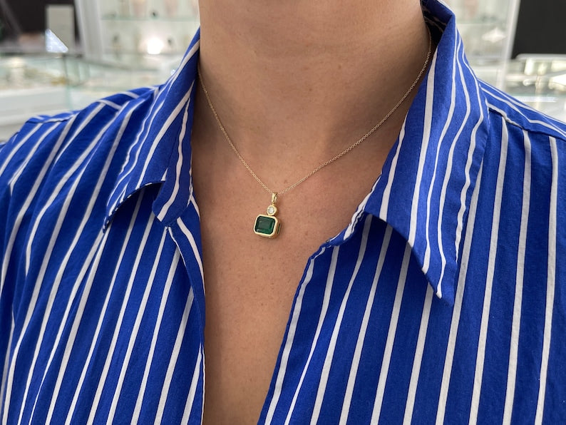 14K green emerald pendant with round diamonds, featuring a lush dark green Colombian emerald and east-to-west setting.