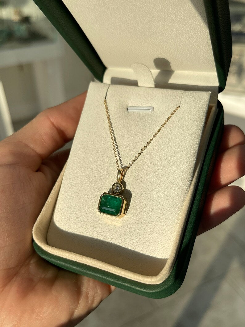 14K Colombian Emerald pendant with 3.60tcw dark green emerald and round cut diamonds, featuring an elegant east-west design.
