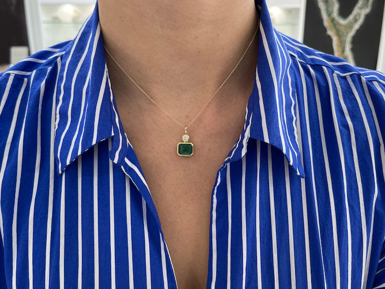 Dark green emerald pendant with round diamonds, 14K gold setting, featuring an east-to-west design and Colombian emerald accents.