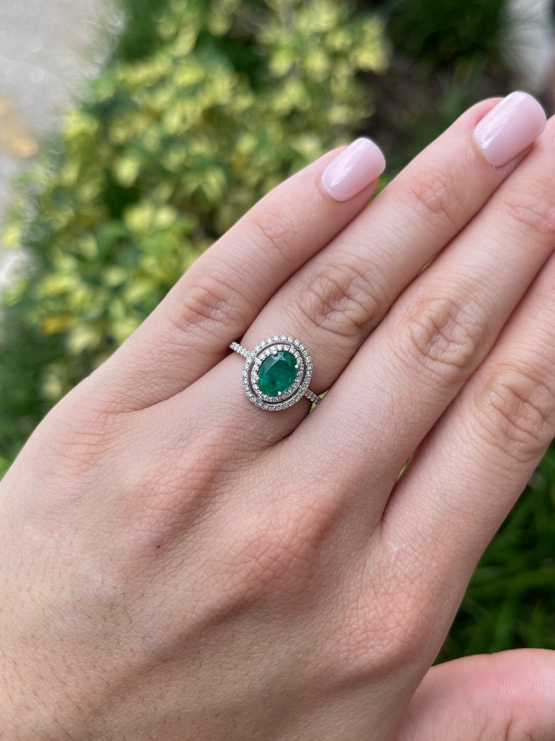 Colombian Emerald engagement ring with 1.90tcw lush green oval-cut emerald and double diamond halo in 14K gold.