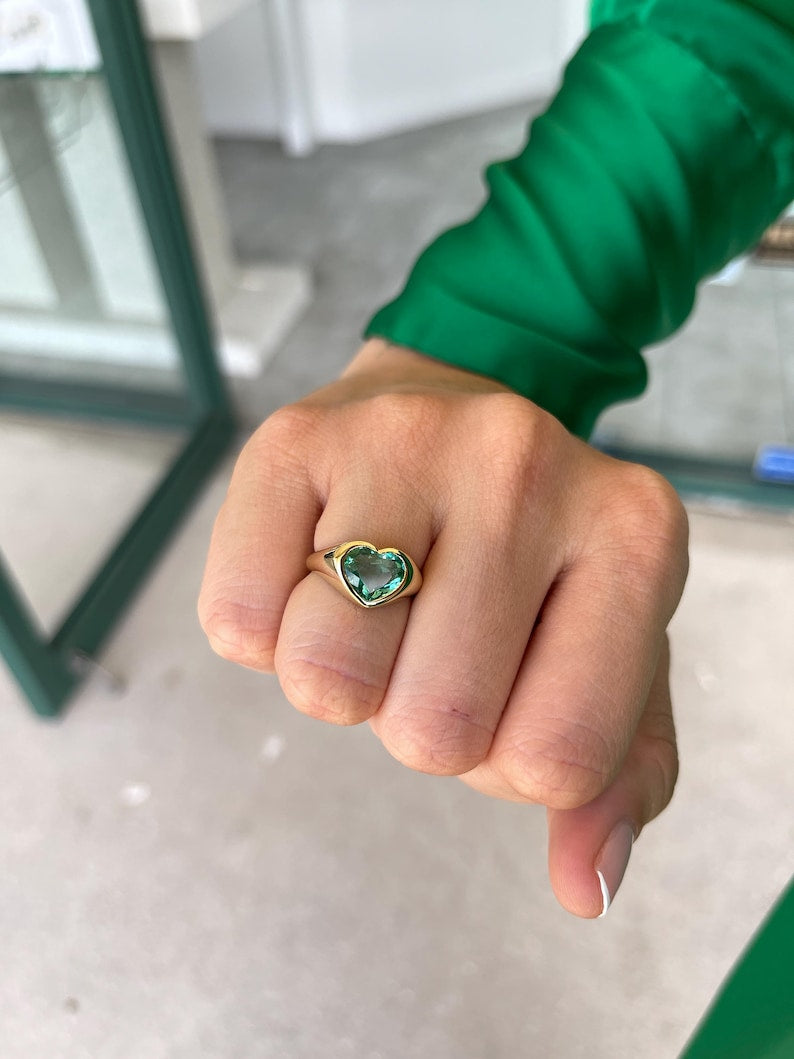 Unisex engagement ring with heart-cut Colombian emerald bezel setting in 18K gold, designed for Nabil and Tara.