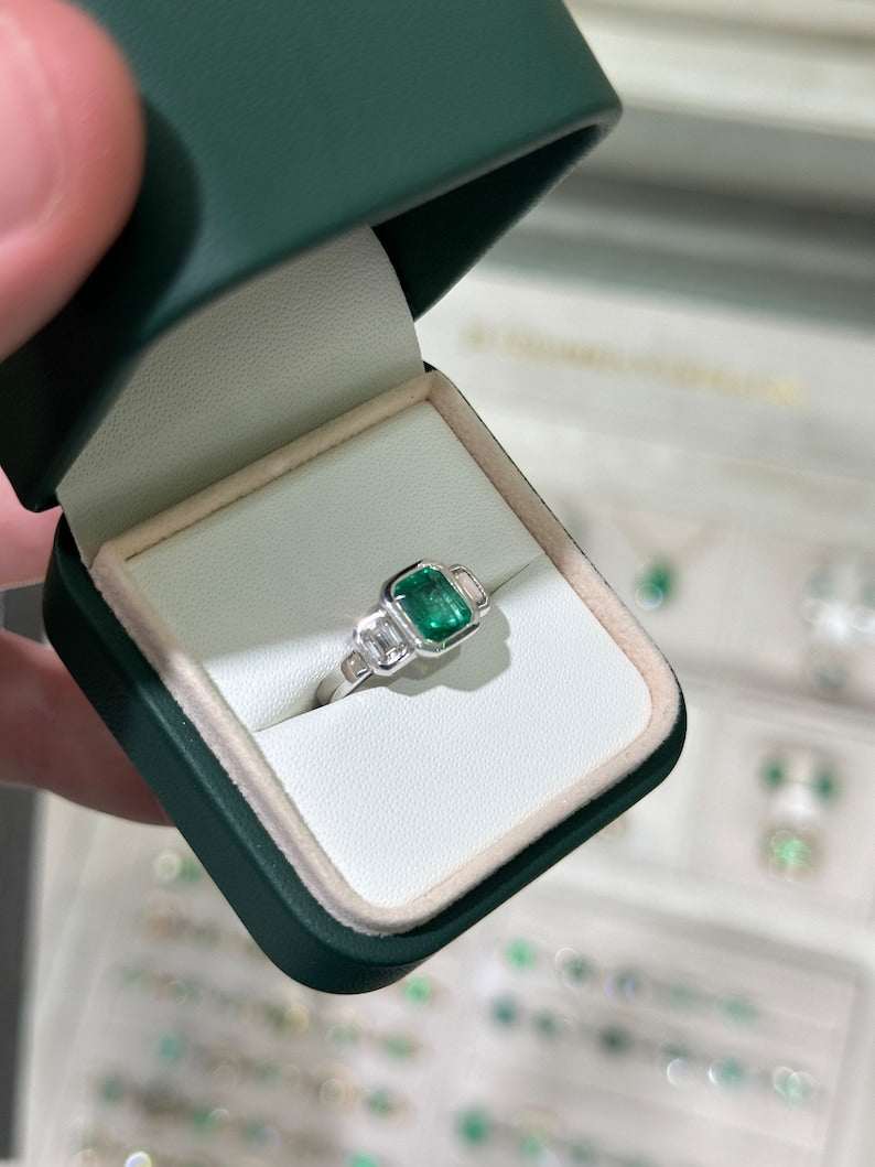 14K gold engagement ring with three natural emerald cut diamonds totaling 2.25 carats, featuring Colombian emerald accents.