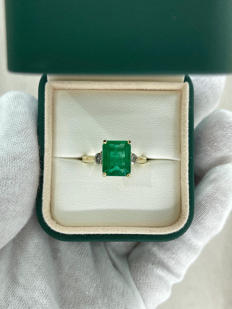 Colombian Emerald engagement ring featuring 4.27ctw green emerald cut and round diamonds in a 14K setting.