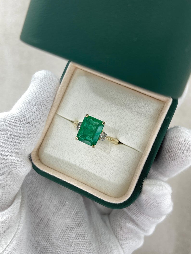 14K green emerald cut and round diamond three-stone engagement ring with 4.27tcw from Colombian Emerald, showcasing elegant craftsmanship.