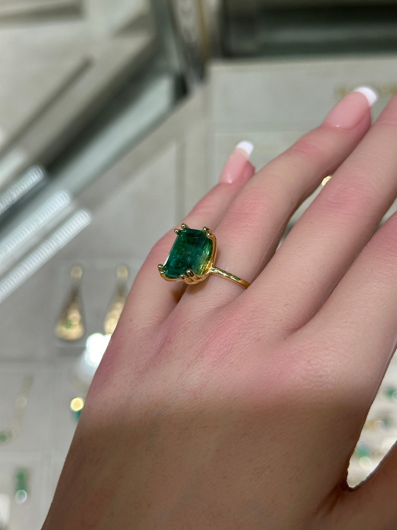 14K Colombian Emerald engagement ring with a 7.35ct emerald cut solitaire gemstone and chunky claw prongs.