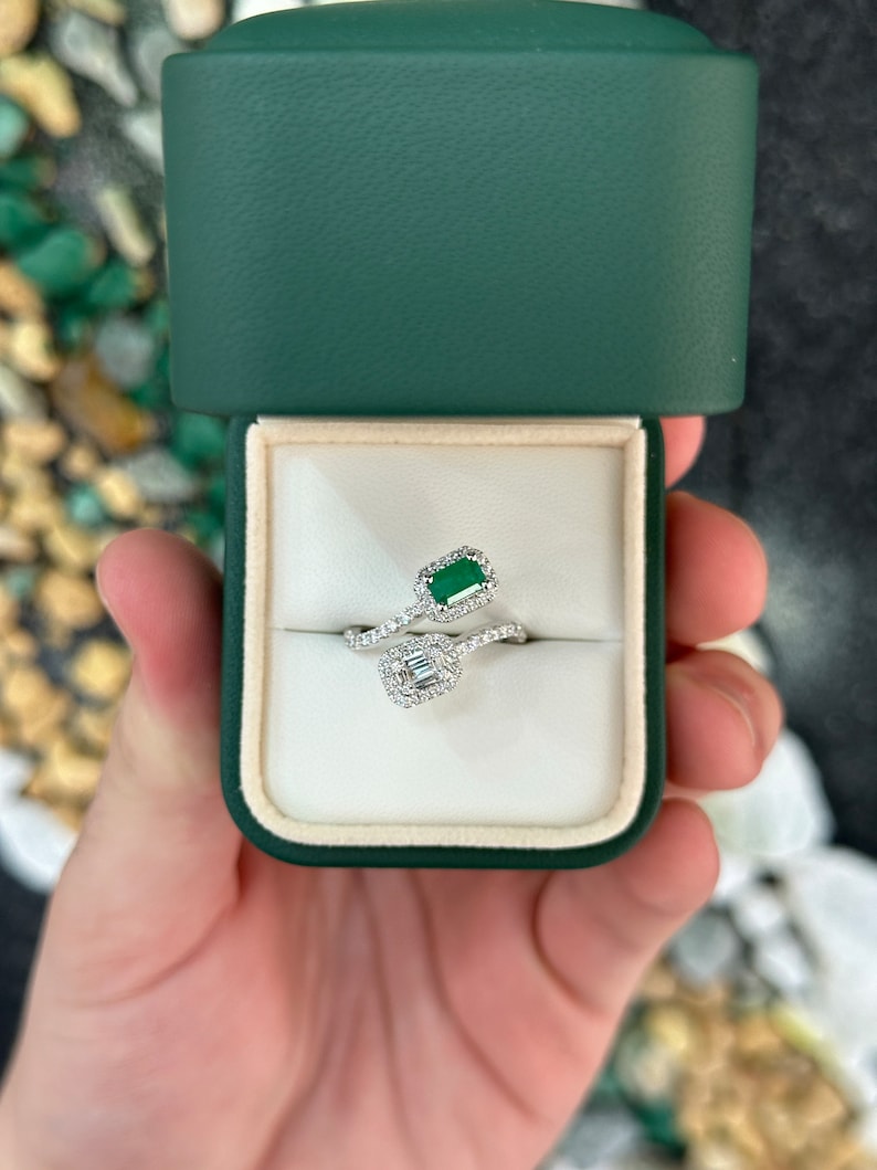 Ladies emerald ring featuring 1.51tcw dark vivid green baguette and round cut Colombian emeralds in a brilliant toi et moi bypass shank design.
