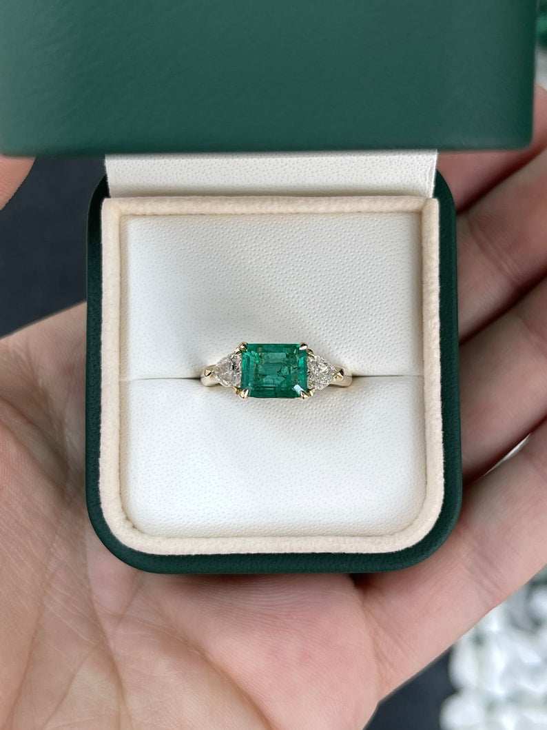 Colombian Emerald ladies ring featuring 2.58tcw 14K gold east-west design with emerald and trillion-cut diamonds in a 3-stone setting.
