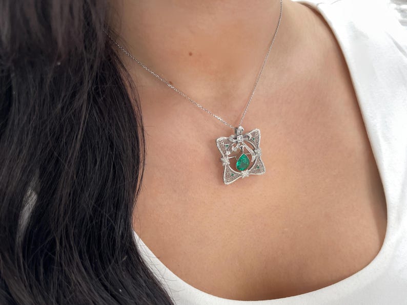 Vintage pendant or brooch featuring a 2.65tcw pear-cut Colombian emerald with diamond accents in 14K gold.